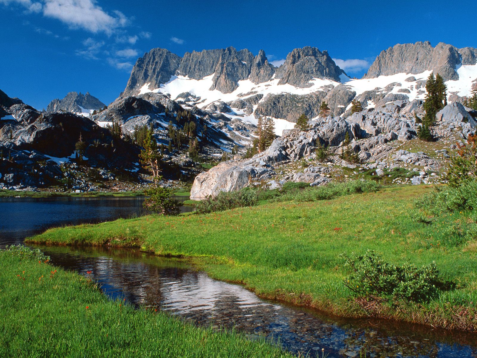 Free photo A green meadow next to snow-covered mountains