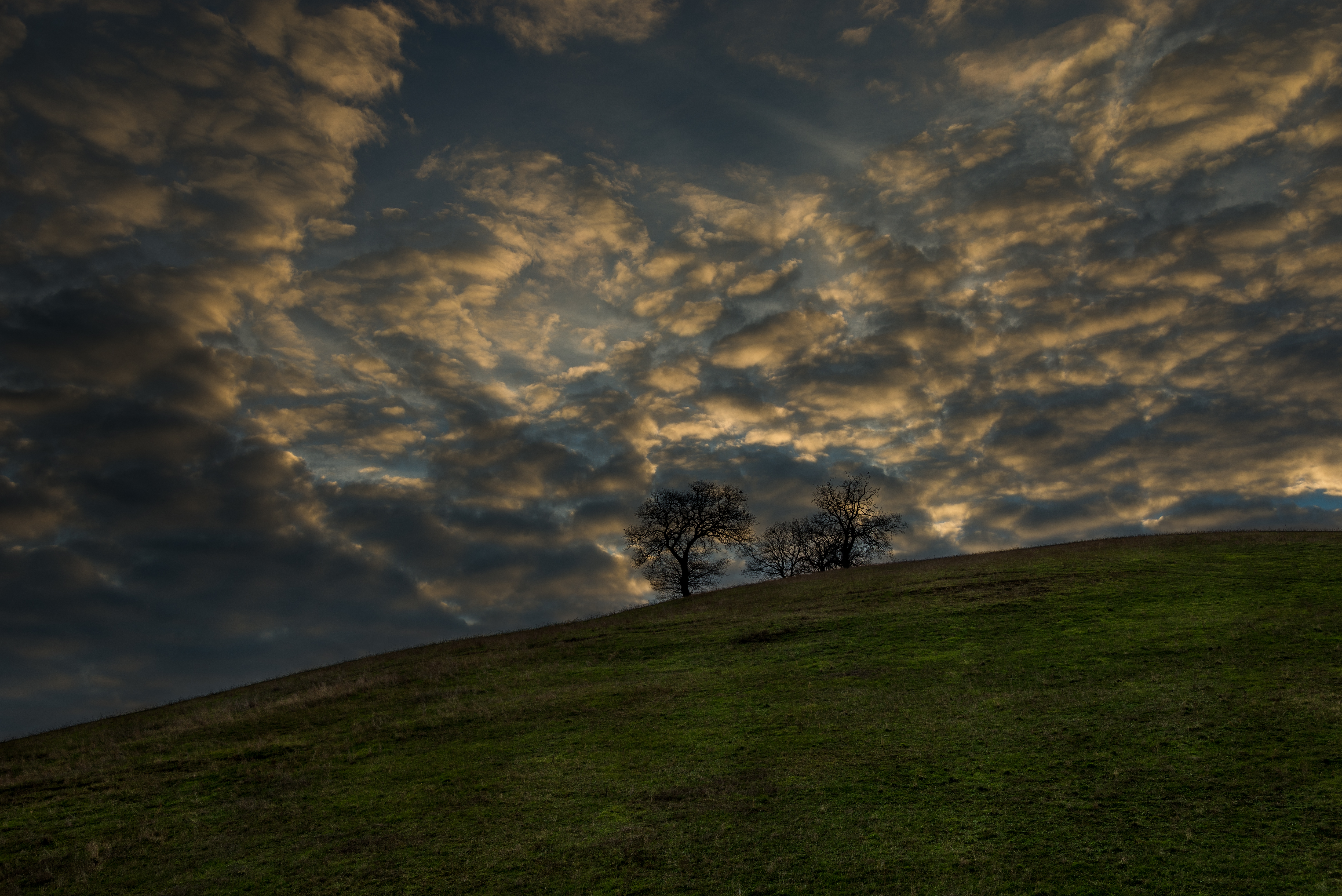 Бесплатное фото Золотые облака над холмом