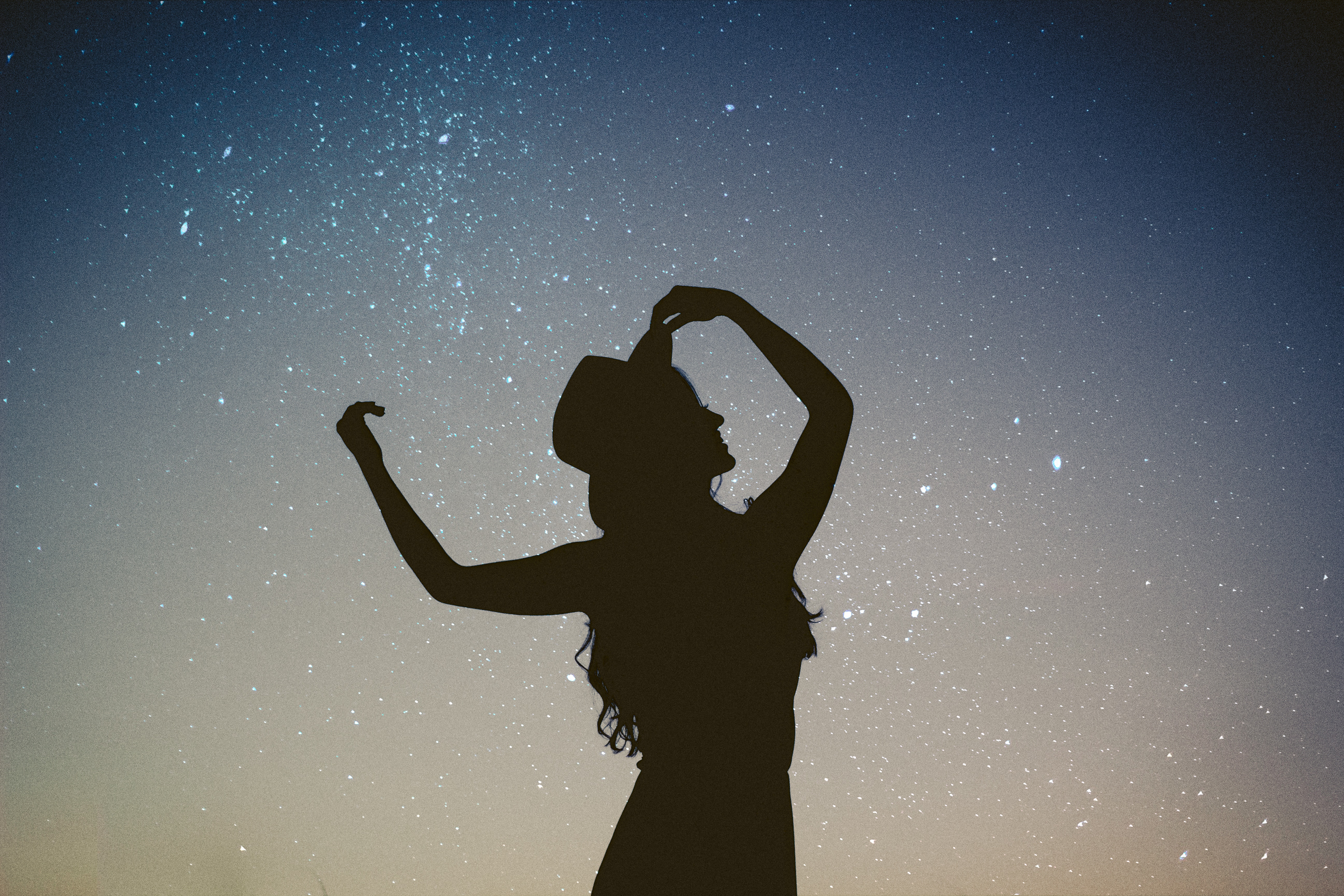 Silhouette of a girl with a hat against the sky