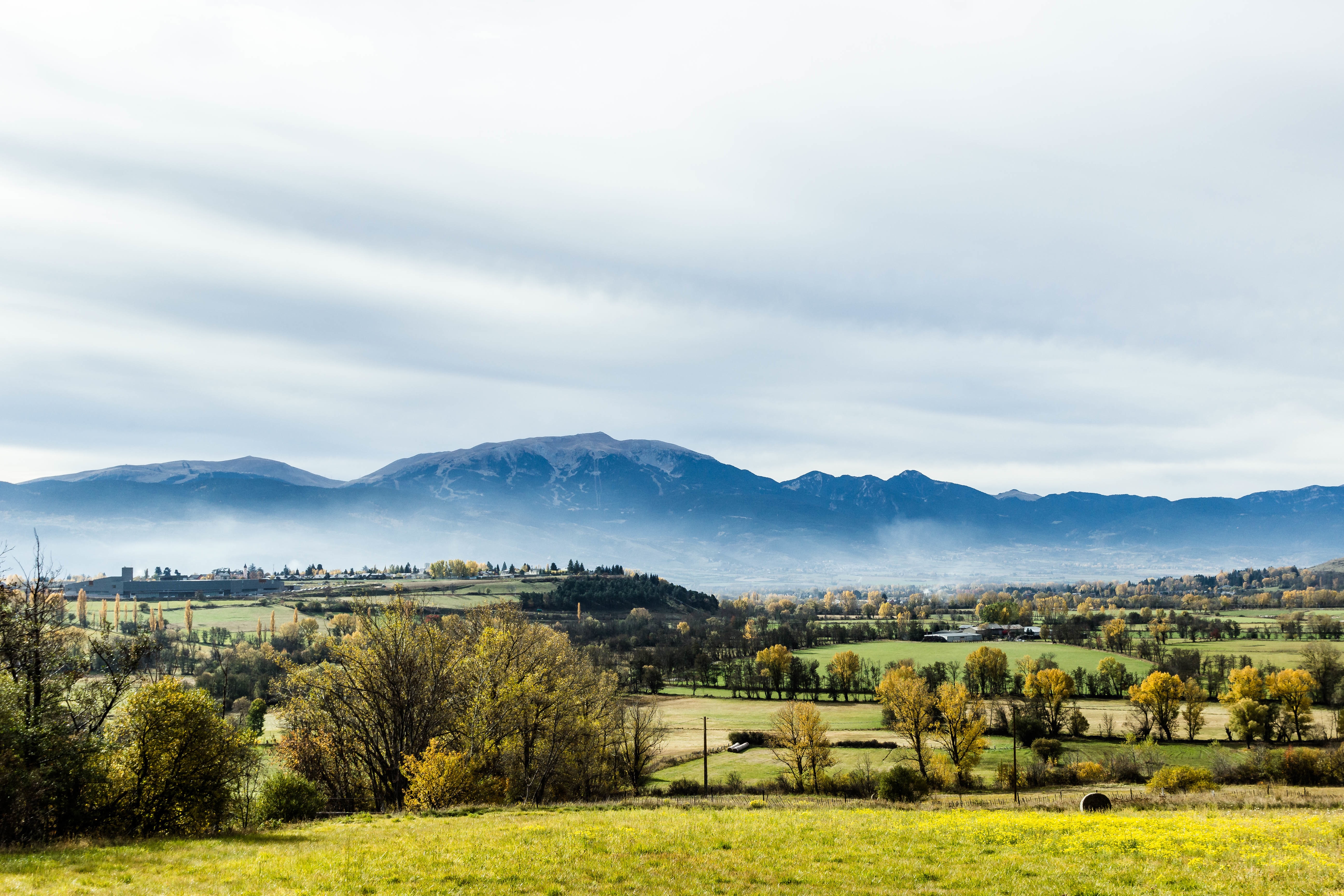 Free photo A pasture with a village in the background of the mountains