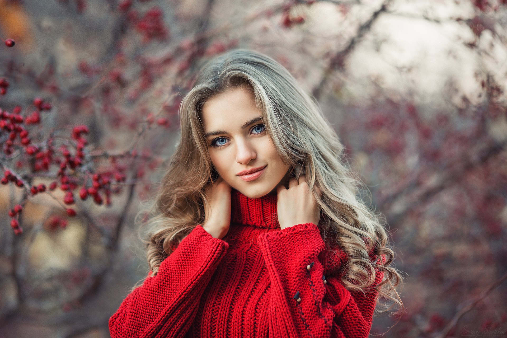 免费照片一个穿着红色高领毛衣的女孩在一棵长满楸树的背景下摆姿势