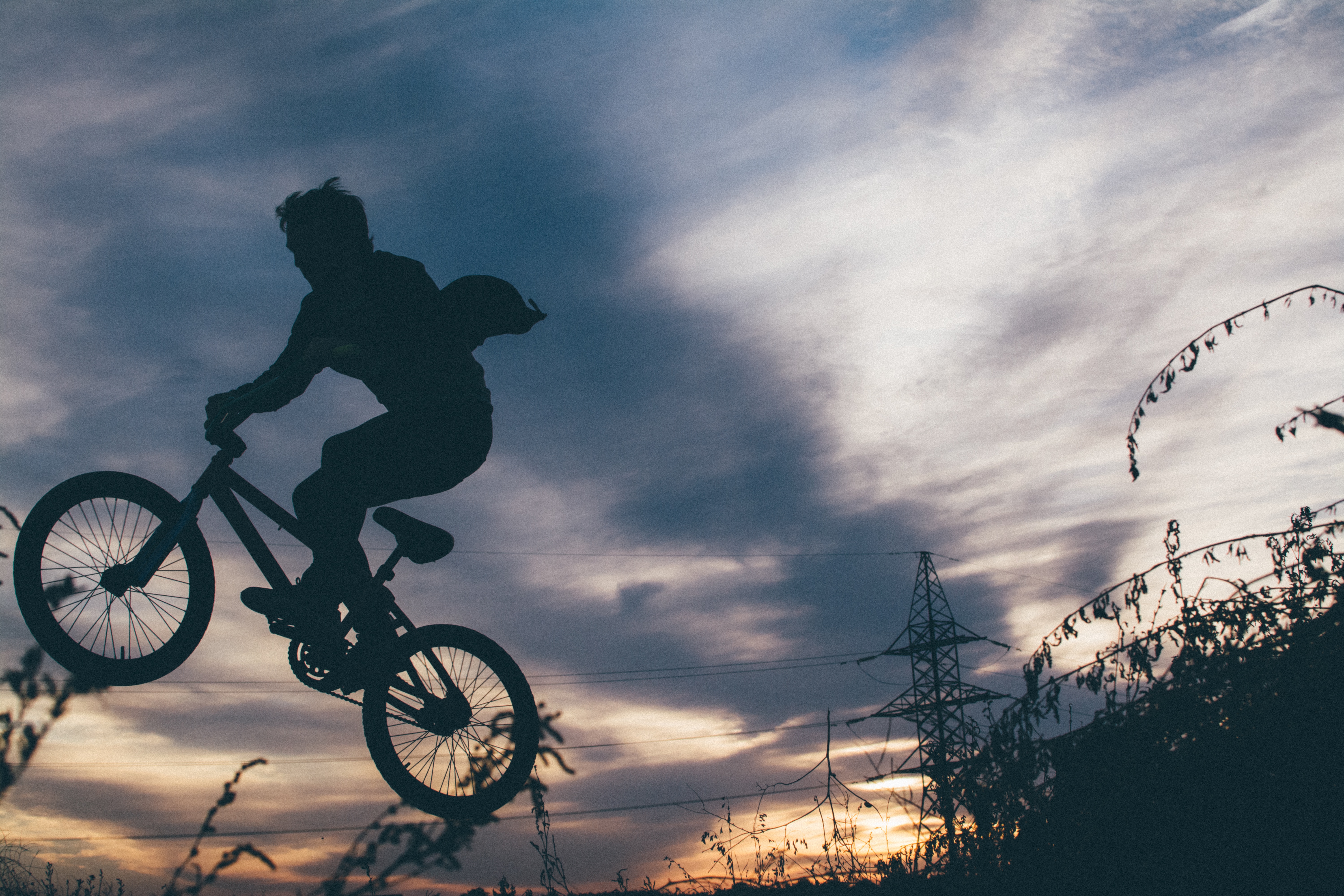 Free photo A silhouette of a boy on a bicycle against the sky