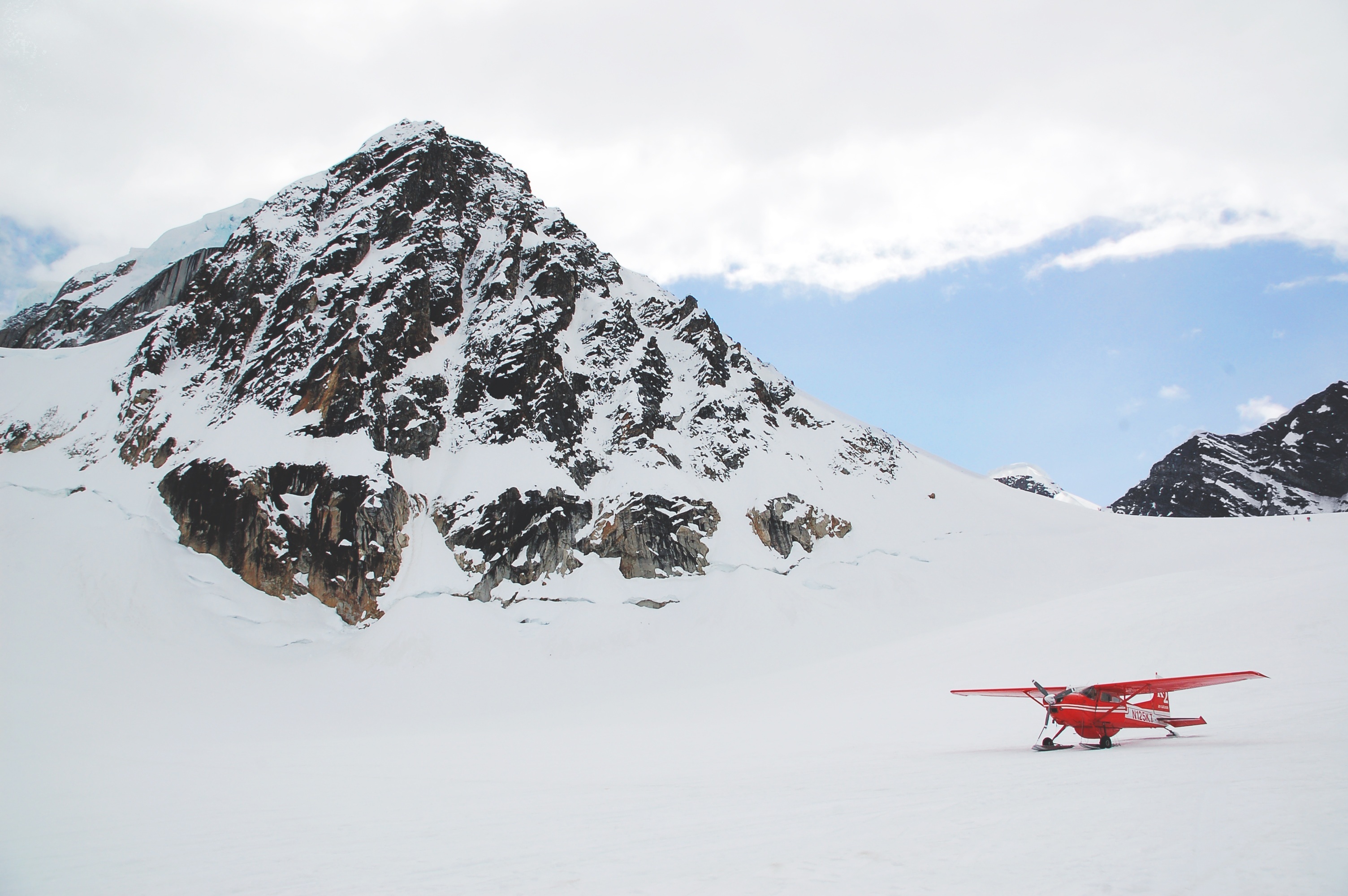 红色私人飞机在北极山区雪中降落