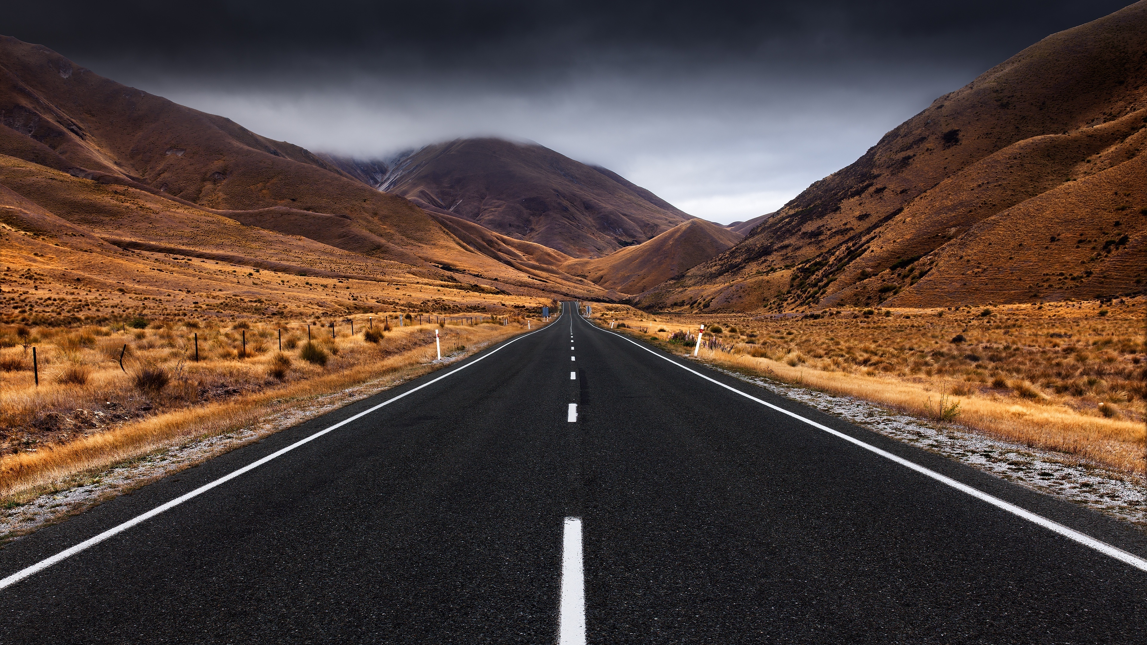 Free photo A long asphalt road at the foot of the mountains