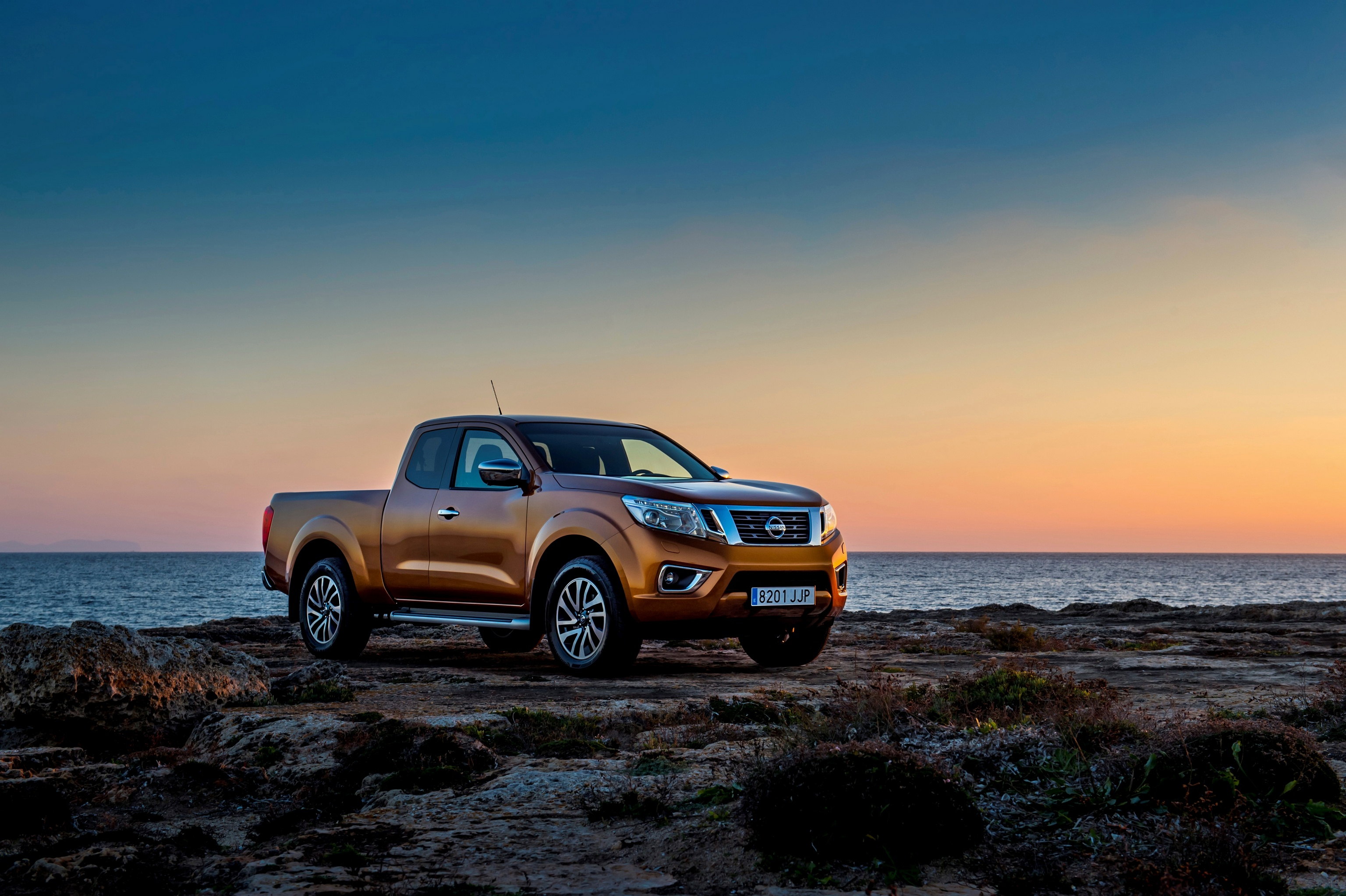 Бесплатное фото Nissan Navara стоит на берегу моря во время заката
