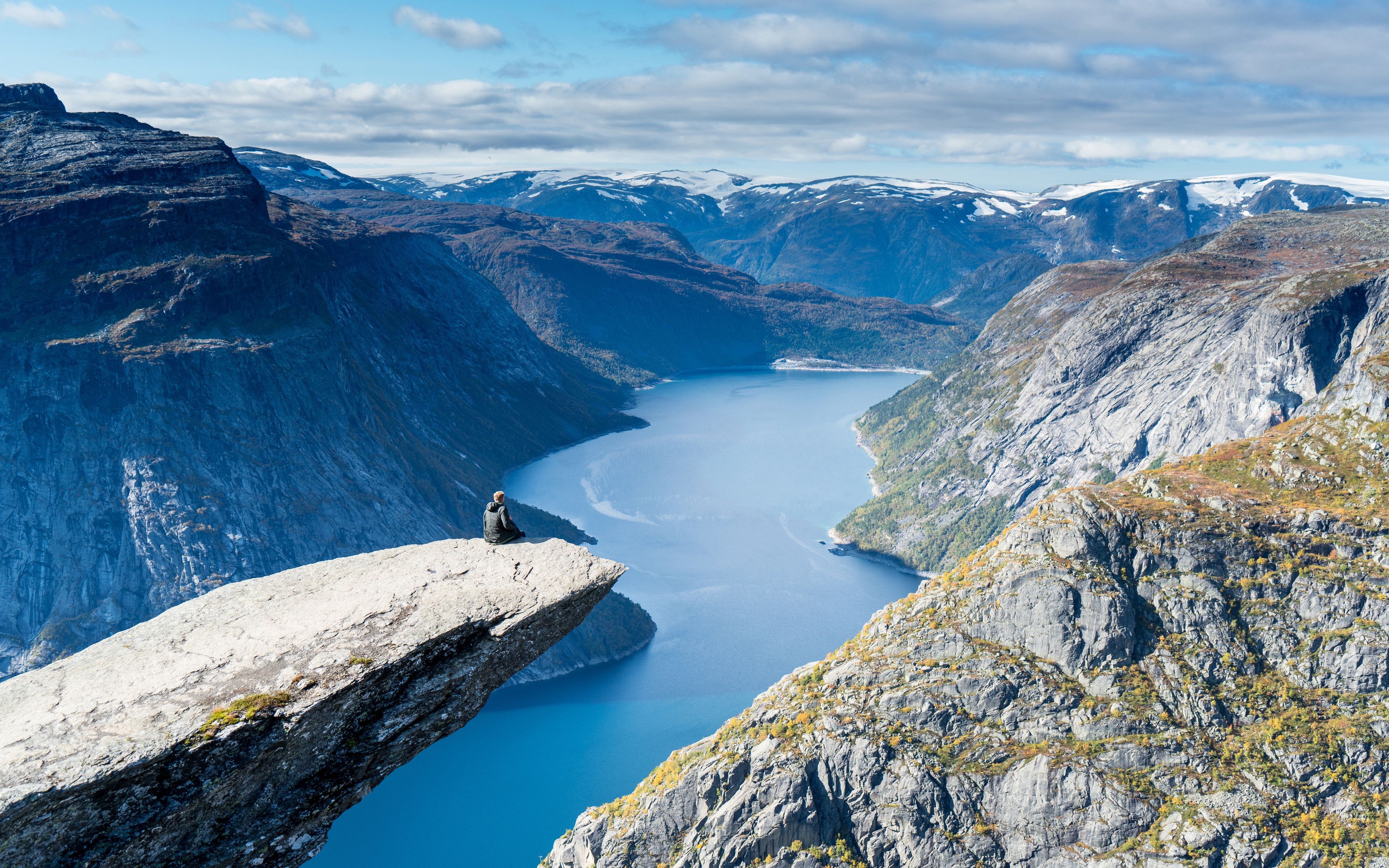 Free photo A man sits on a rock above the ocean in the mountains