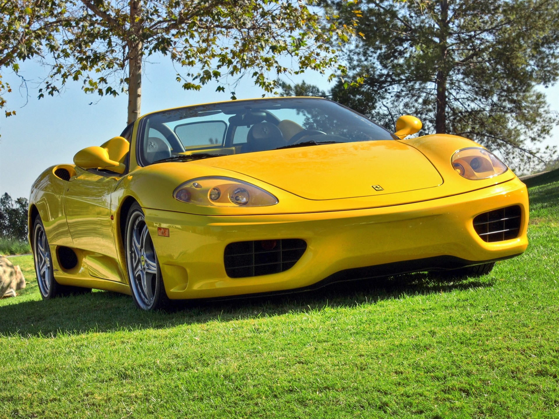 Free photo A yellow ferrari 360 convertible standing on a green lawn