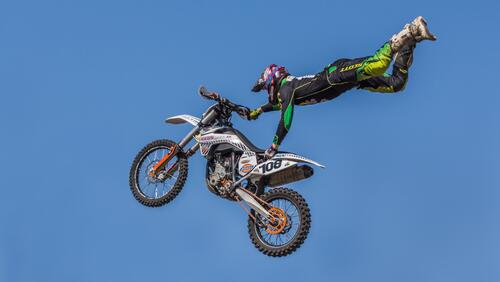 Бесплатное фото Мотоциклист в полете тянется к мотоциклу