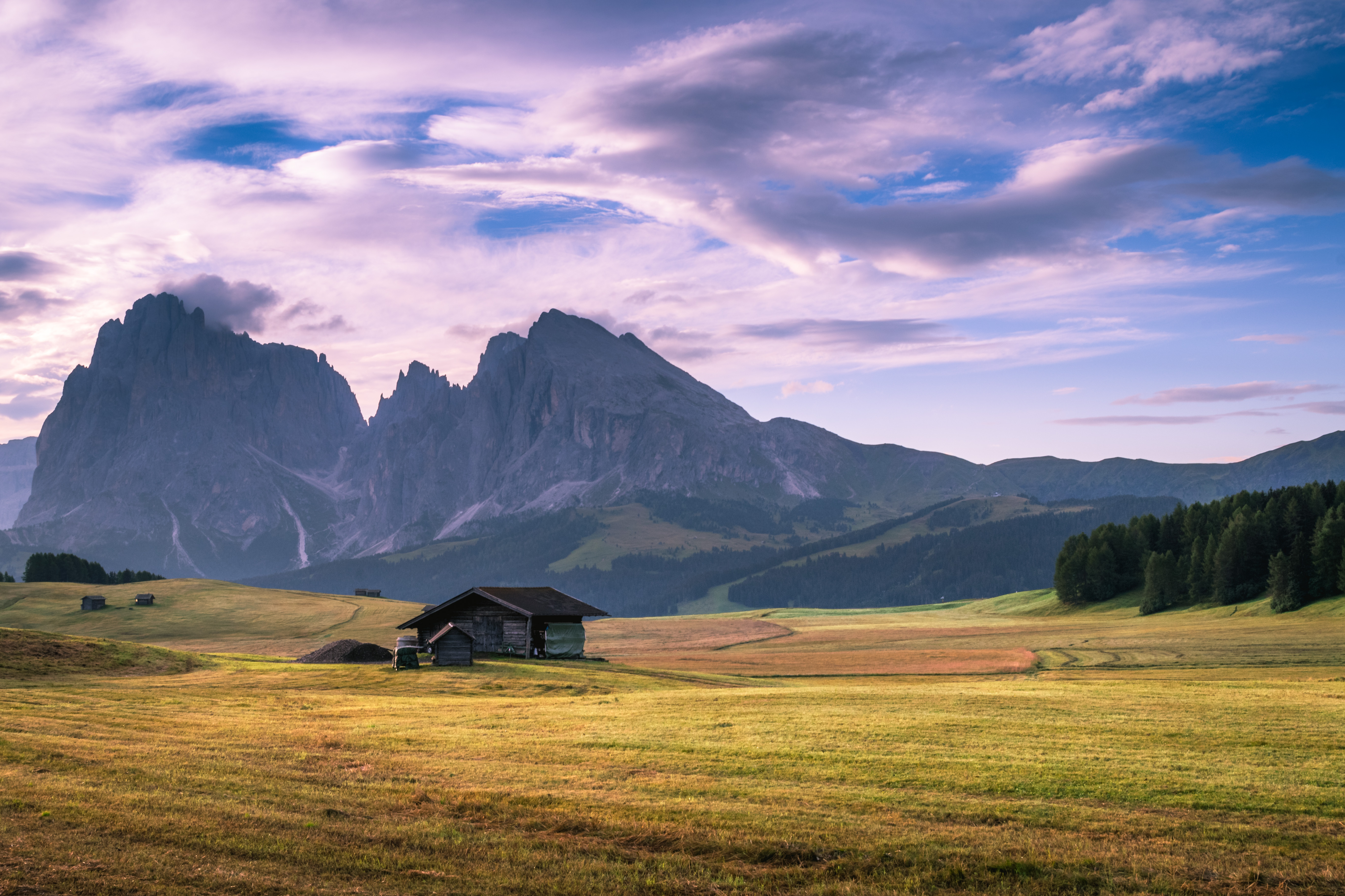 Free photo An old house in a field with the mountains as a backdrop