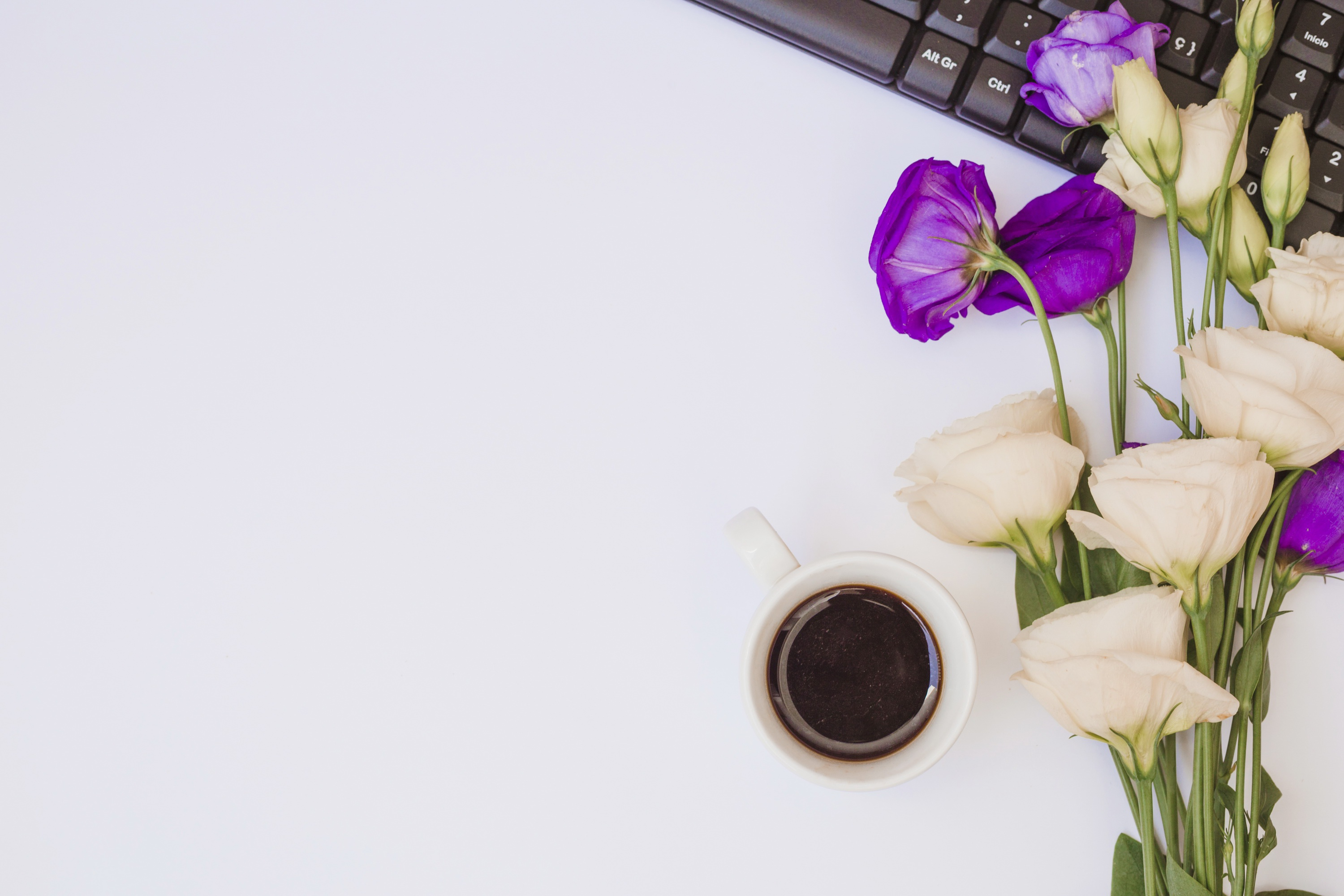 Purple flowers lies on a computer desk with a cup of tea