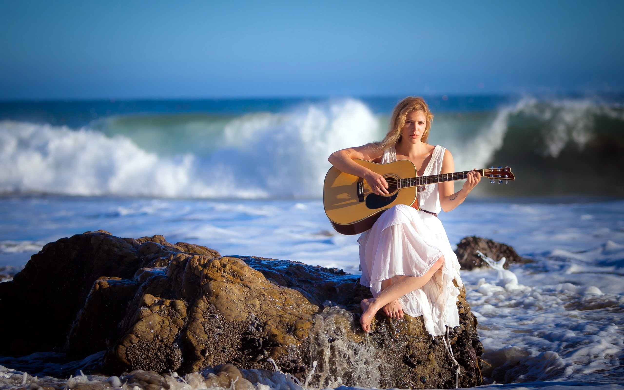 穿着白色连衣裙的女孩在海边弹吉他