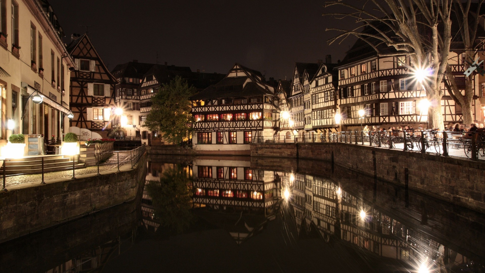 Night view of the canal with illuminated half-timbered houses reflected in the water.