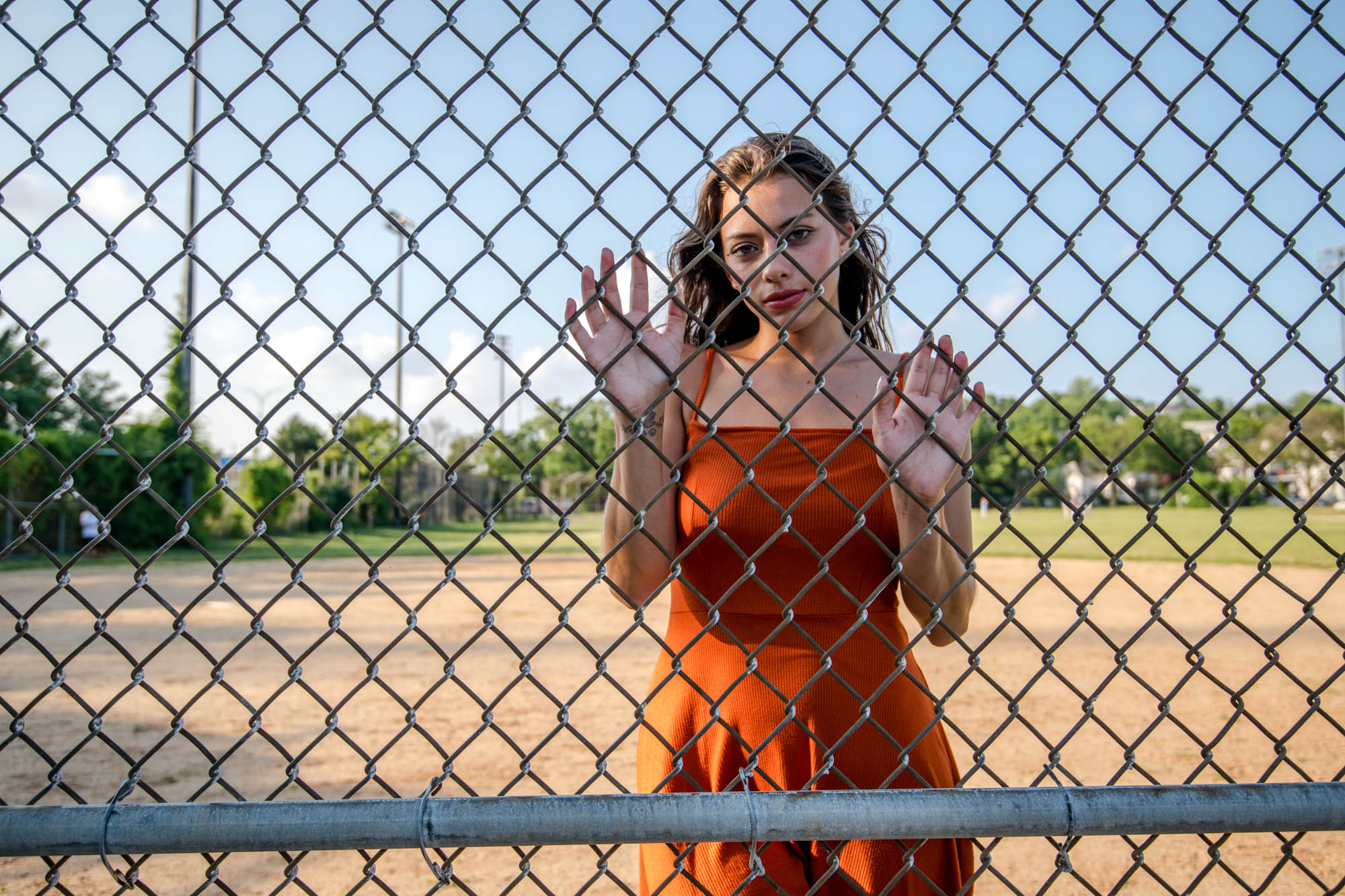 Free photo The girl in the orange dress is standing behind the fence