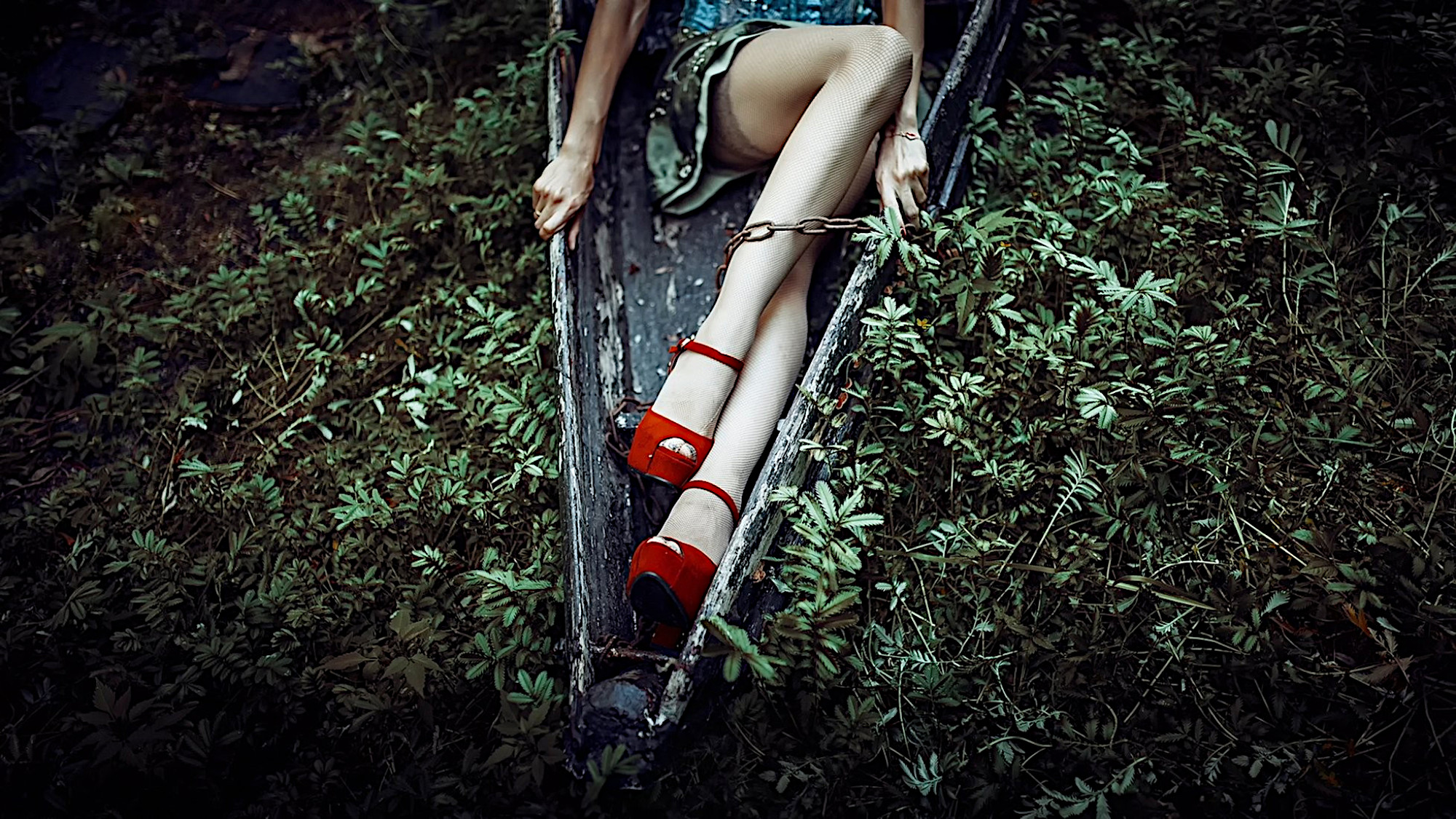 A girl in red heels in the woods.
