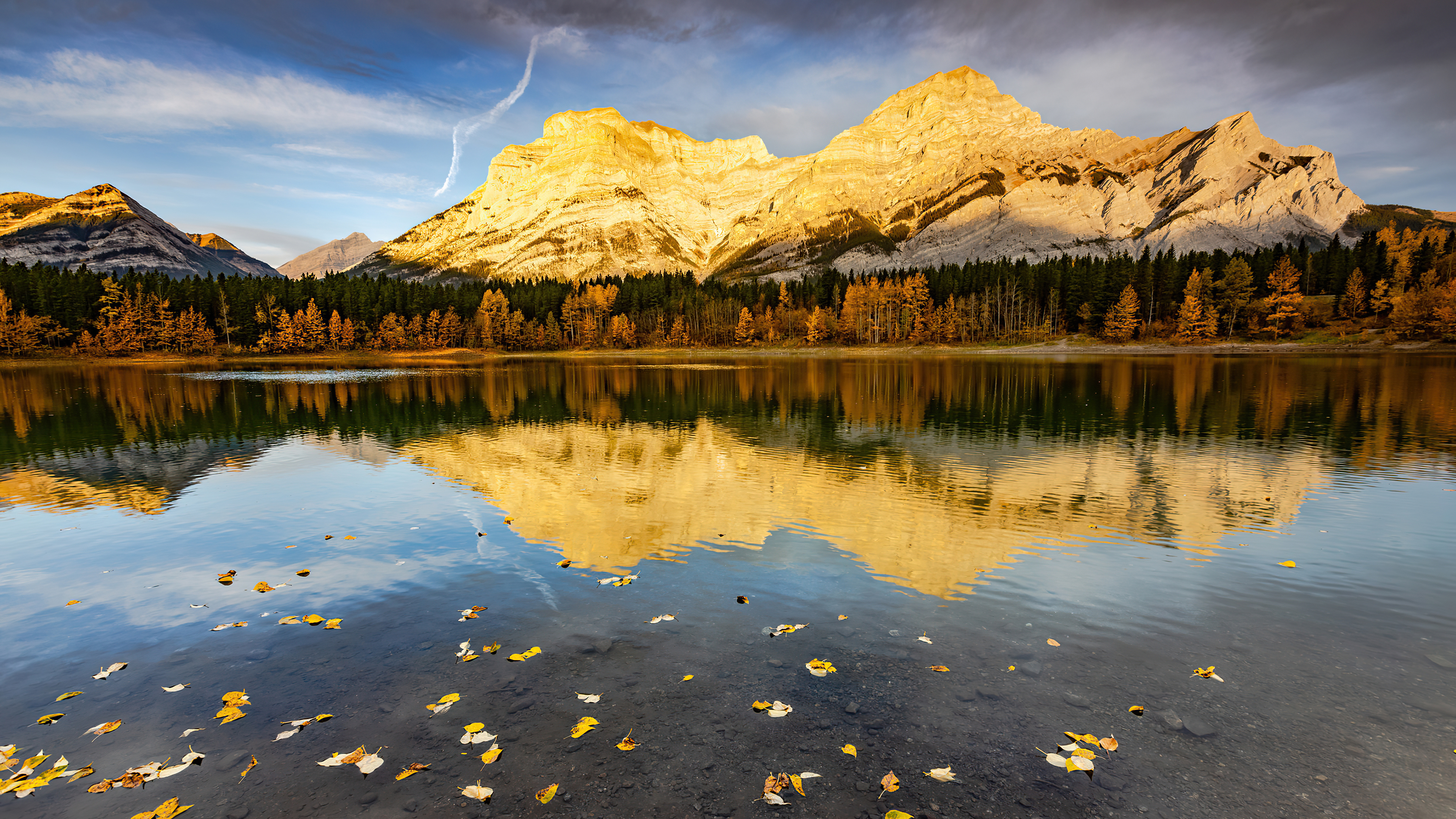 The sunlit mountains are reflected in the lake