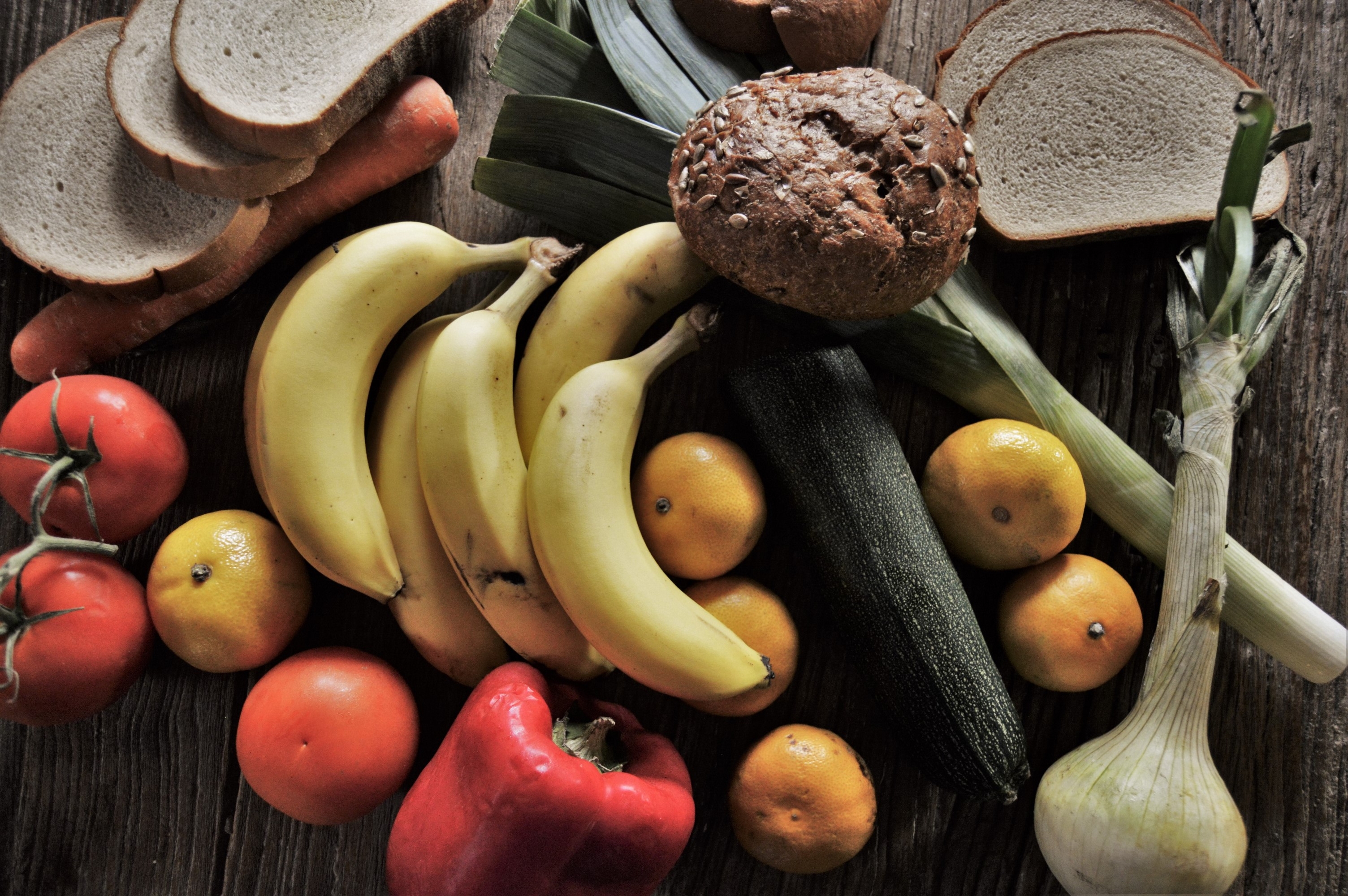 Free photo Fruit and bread scattered around the table.