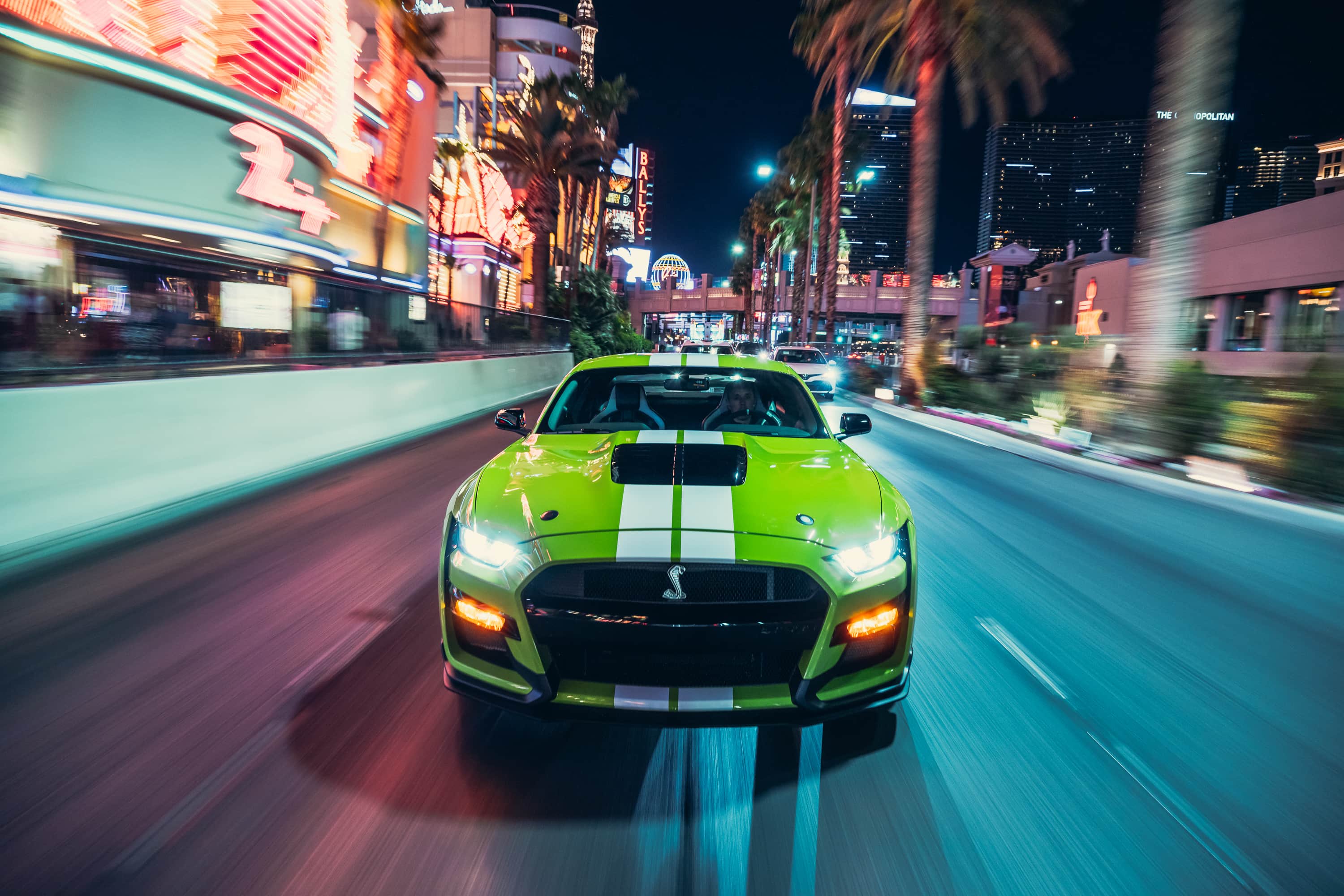 Free photo A yellow Ford Mustang driving down a street at night.