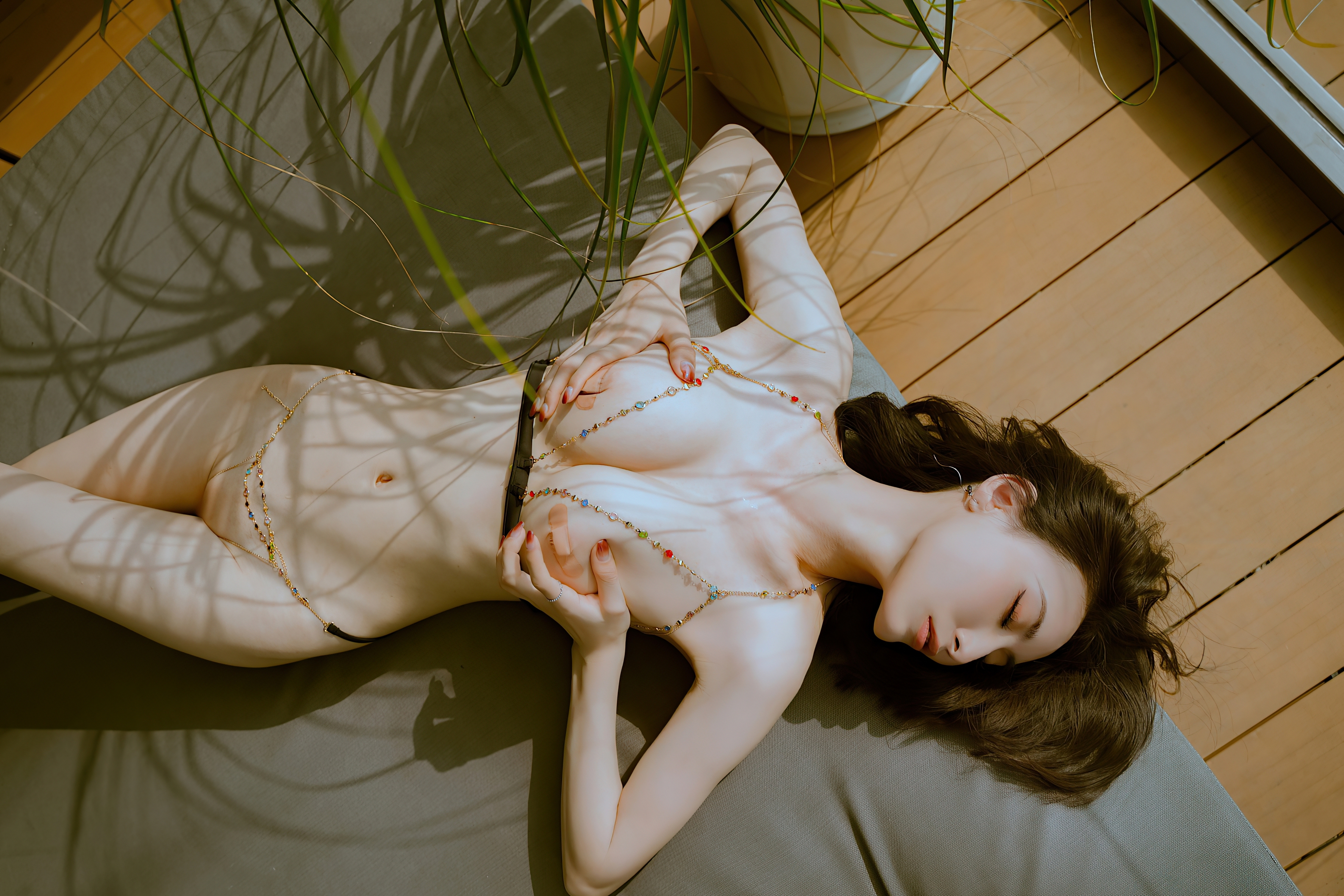 Free photo Beautiful Chinese woman nude lying on the floor clutching her breasts with her hands