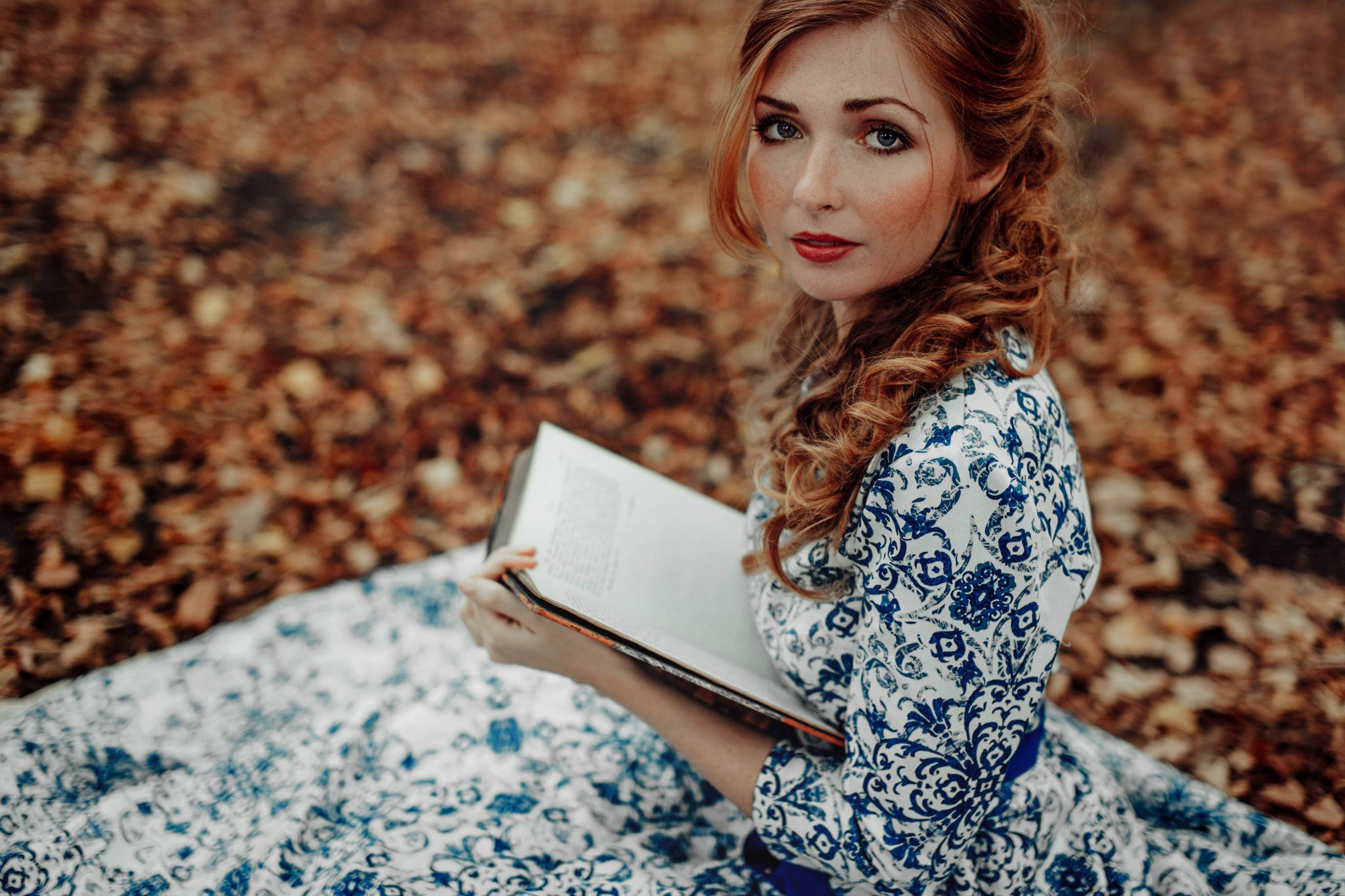 一个身穿蓝色图案的白色连衣裙的女孩正在阅读一本书