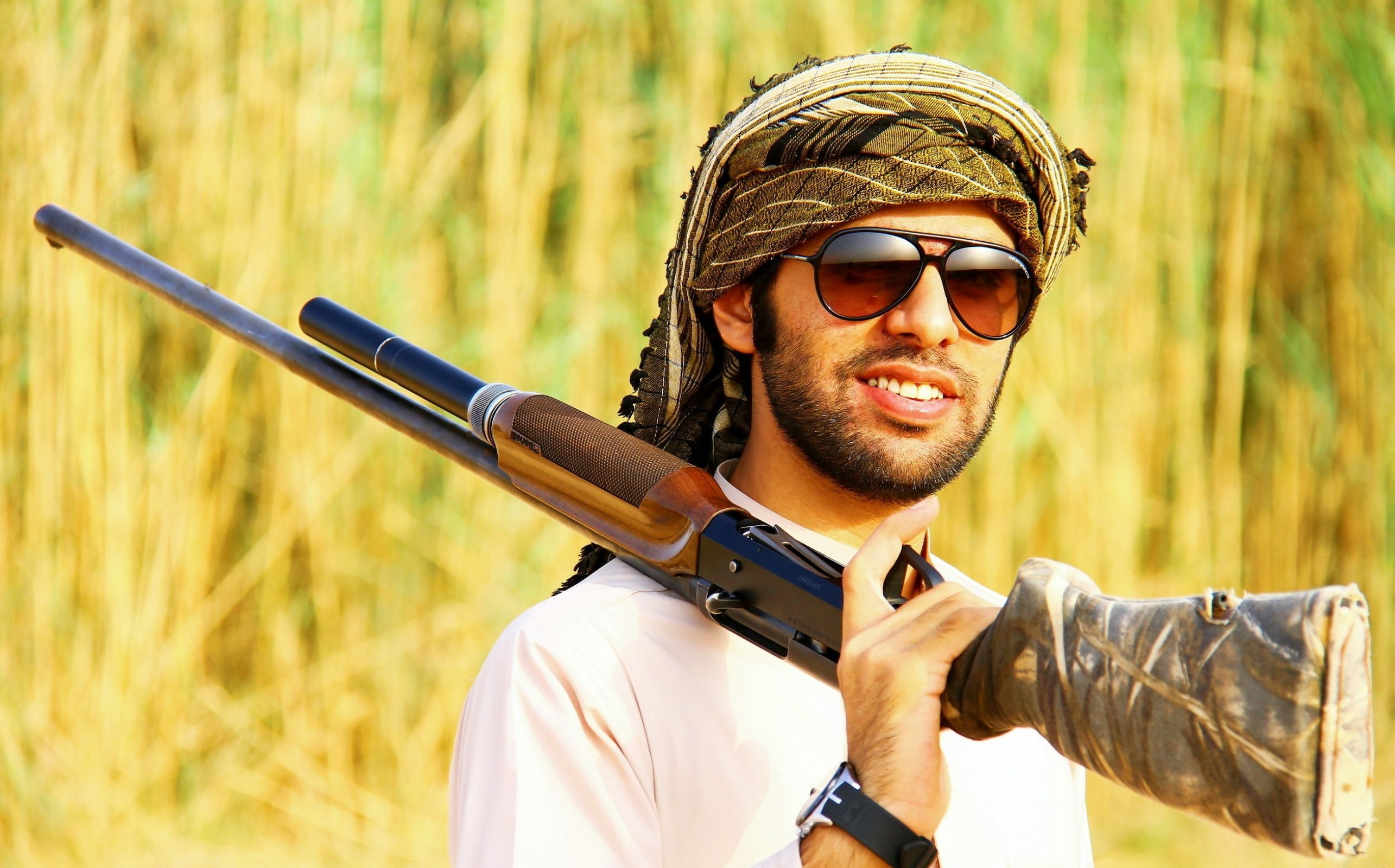 戴墨镜的阿拉伯男子手持猎枪。
