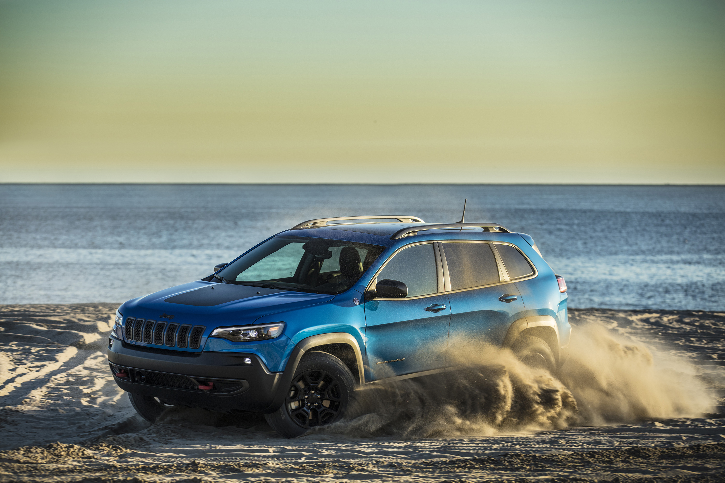 Бесплатное фото Jeep cherokee trailhawk едет по песку на пляже