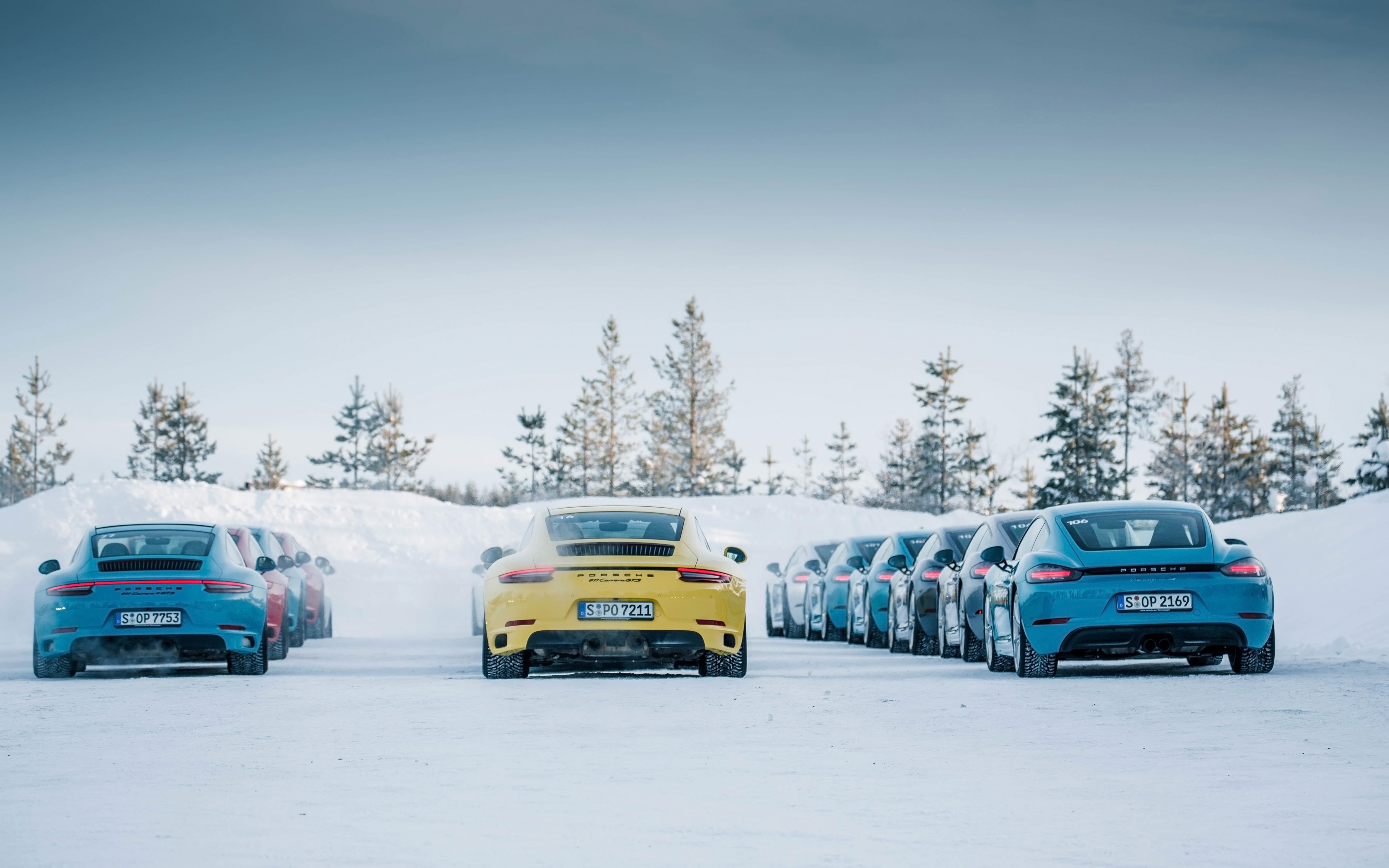 A large convoy of porsche 911s on a winter road