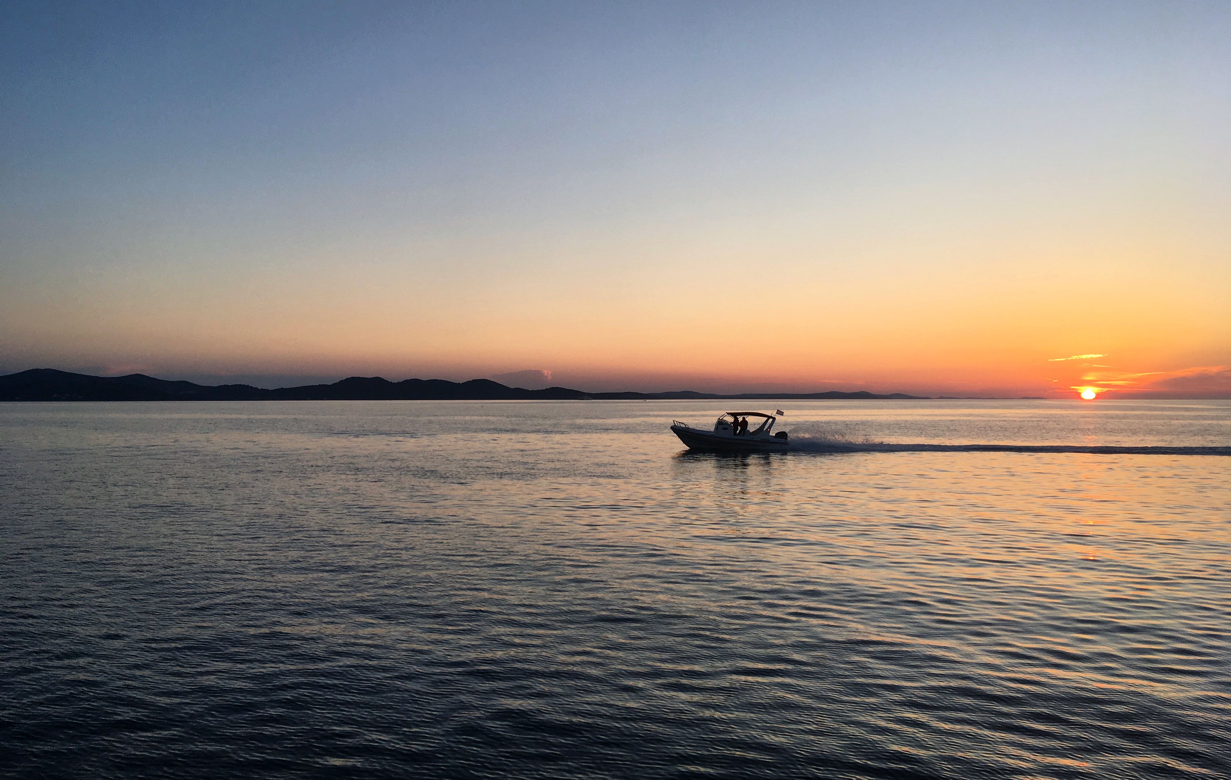 Free photo A boat with a motor floats down a river at sunset