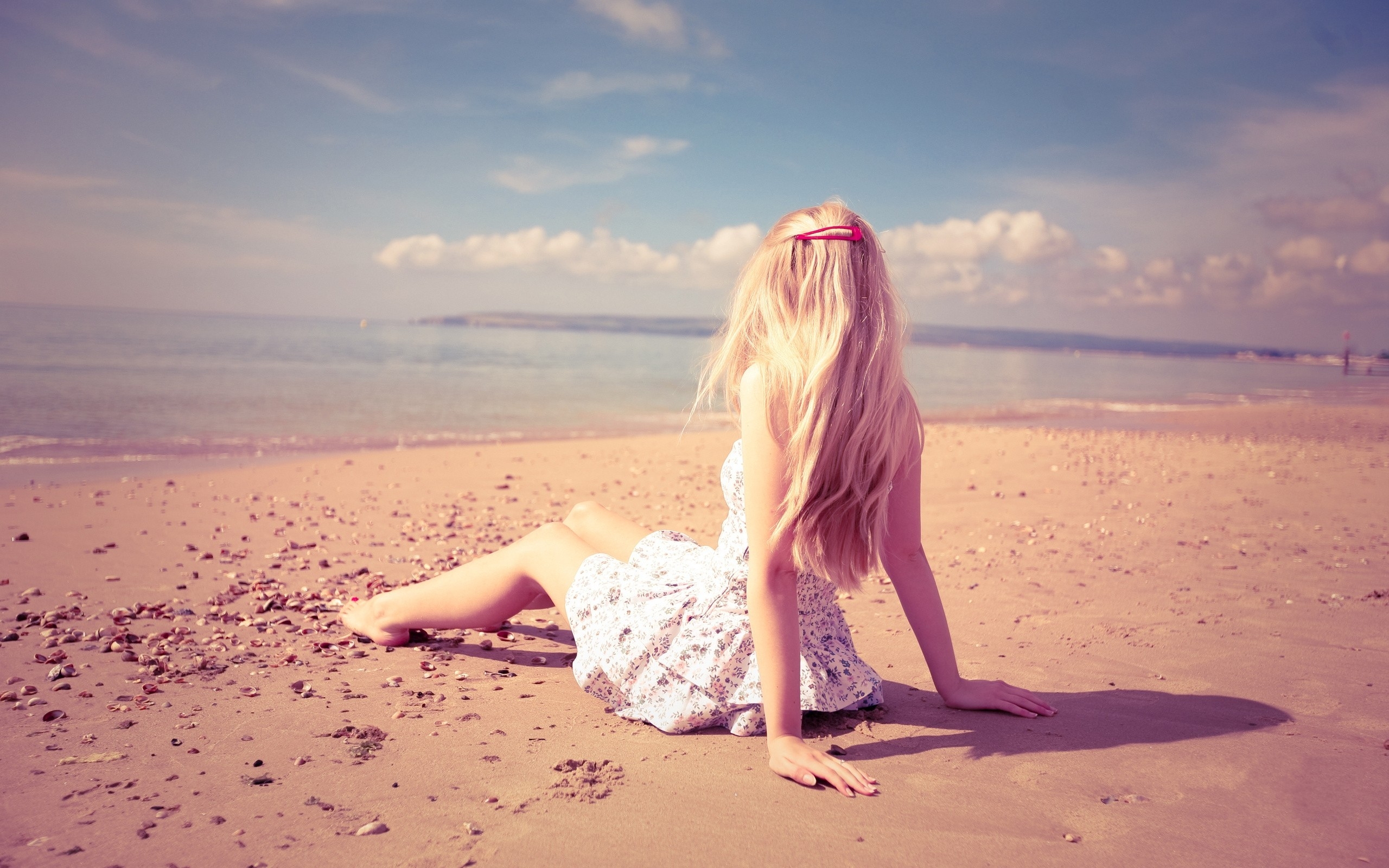 免费照片一个穿着裙子的金发女孩坐在海边