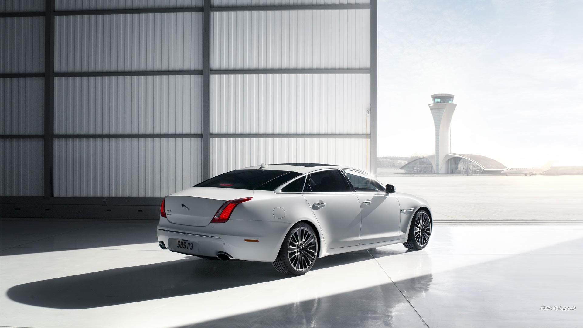 Free photo A white Jaguar XJ in an airplane hangar.