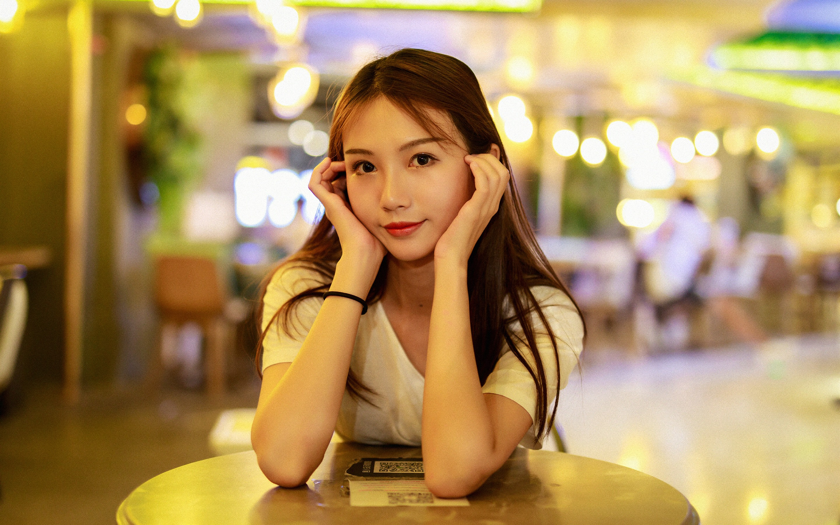 Free photo A beautiful Chinese woman at a table in a street coffee shop