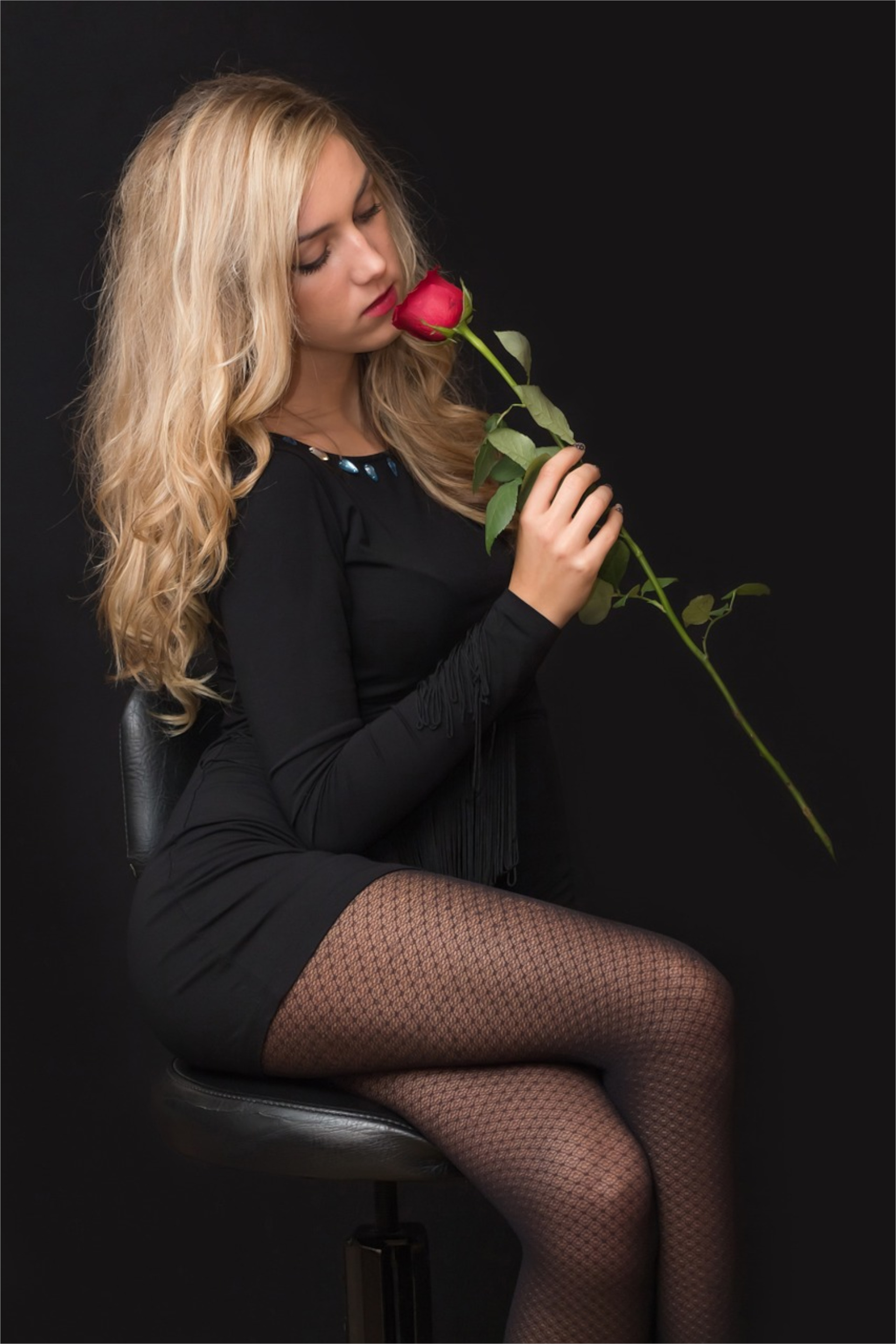 免费照片穿着黑色晚礼服的金发女郎，带着一朵红玫瑰