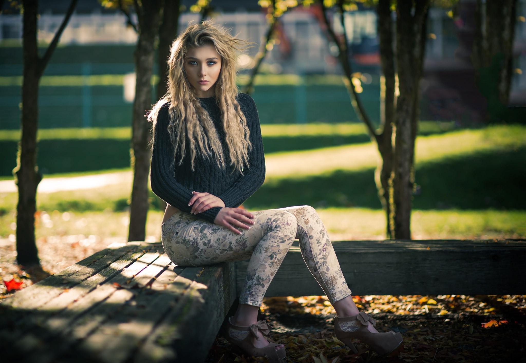 Free photo A curly-haired girl sits on a park bench