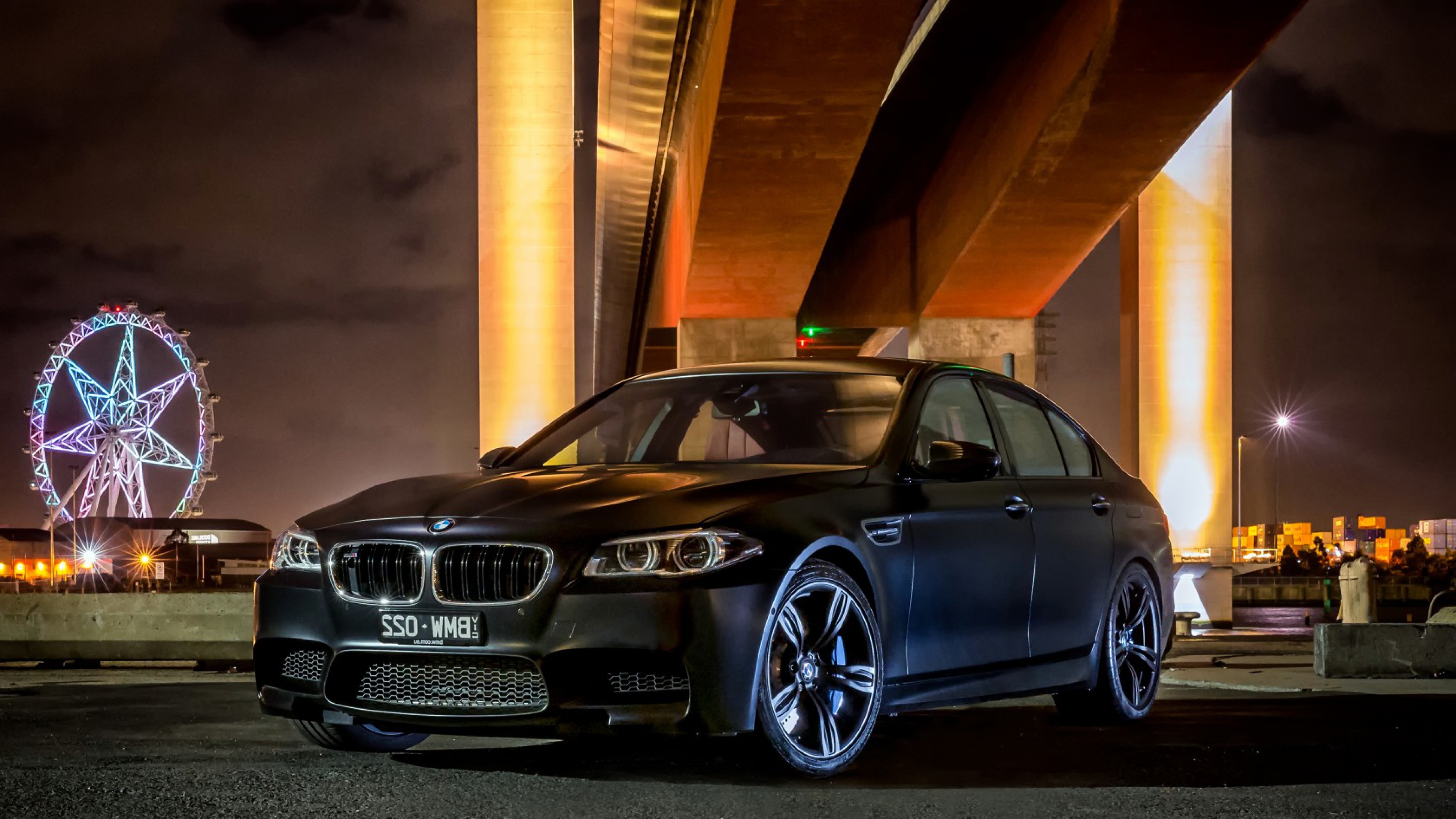 Free photo Black matte BMW M5 stands under the bridge