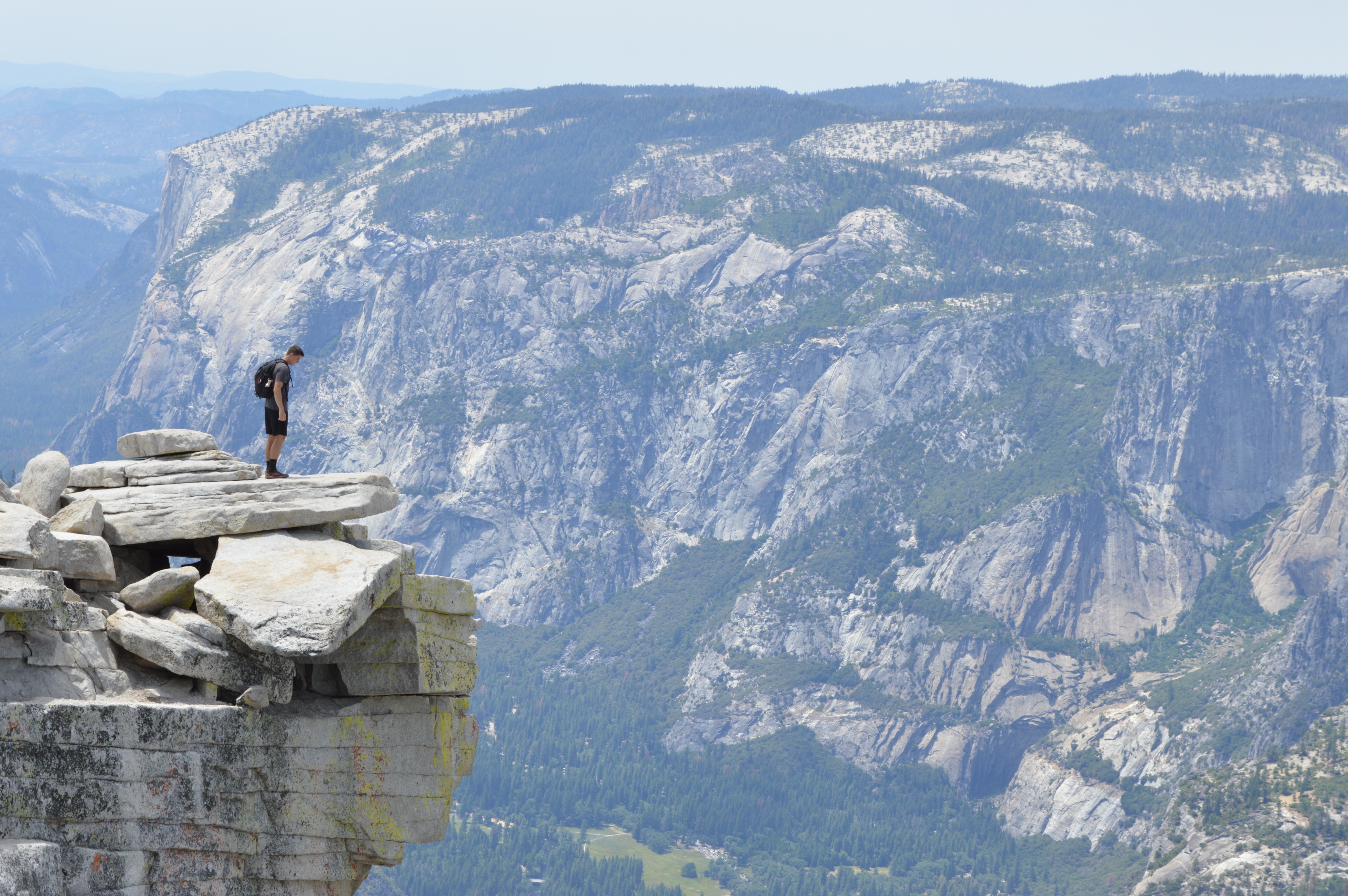 一个男性旅行者站在悬崖峭壁上，往下看