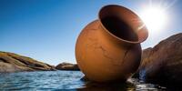 Треснувший глиняный сосуд, покоящийся у скалистого берега.