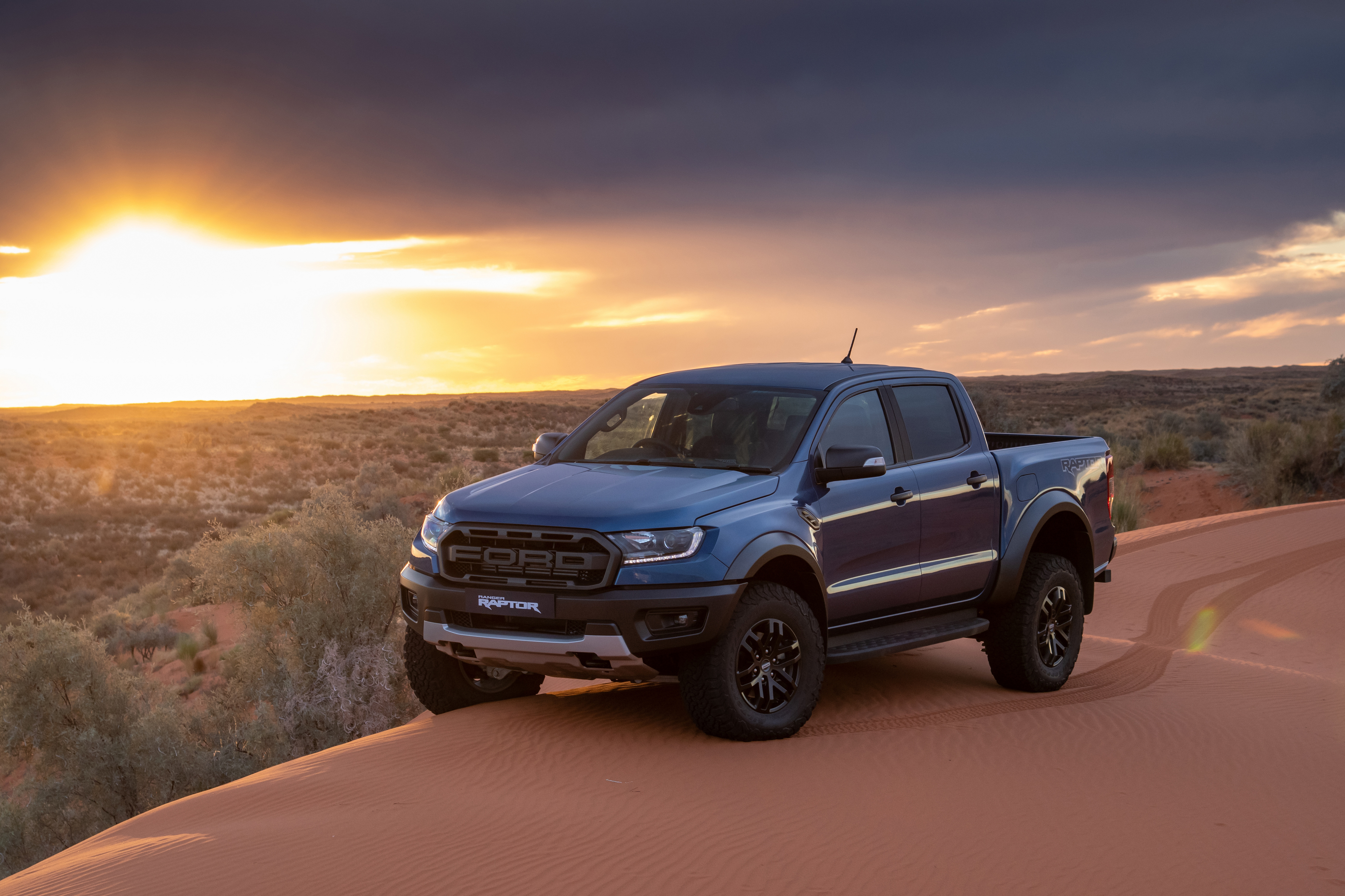 The 2019 Ford Ranger Raptor in blue drives over sand dunes