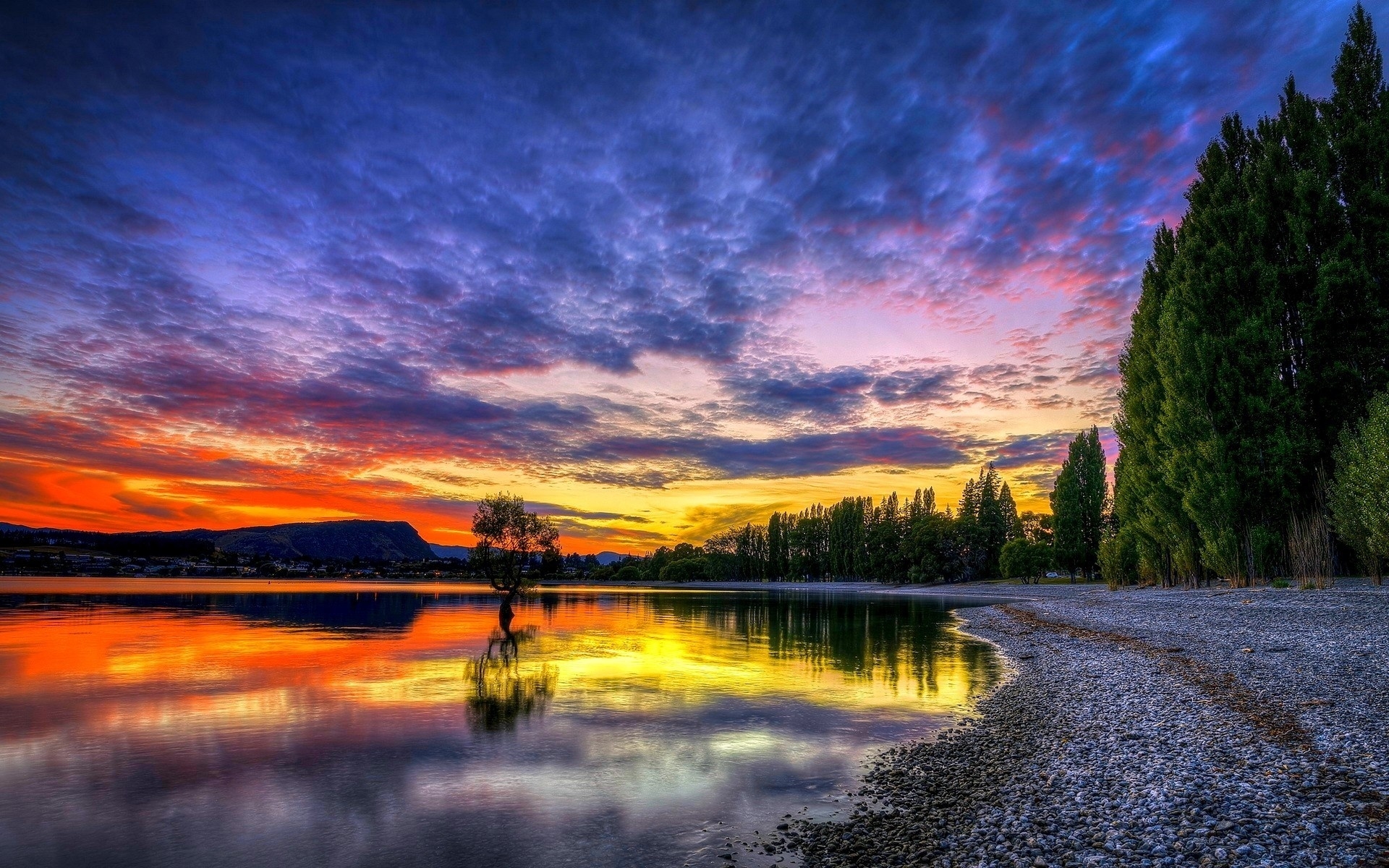 Free photo A bright sunset on the shore of the lake with pebbles