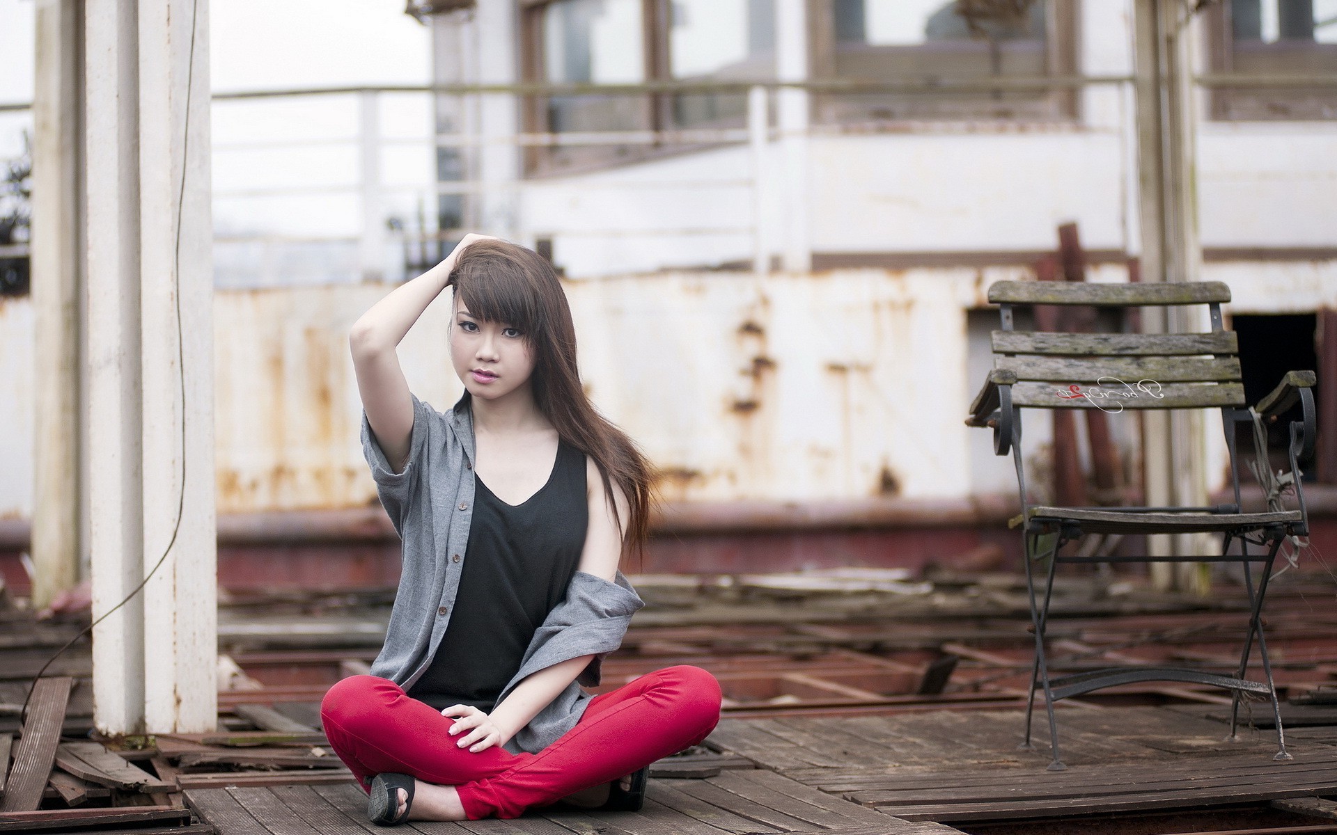 An Asian-looking brunette sits on a wooden floor