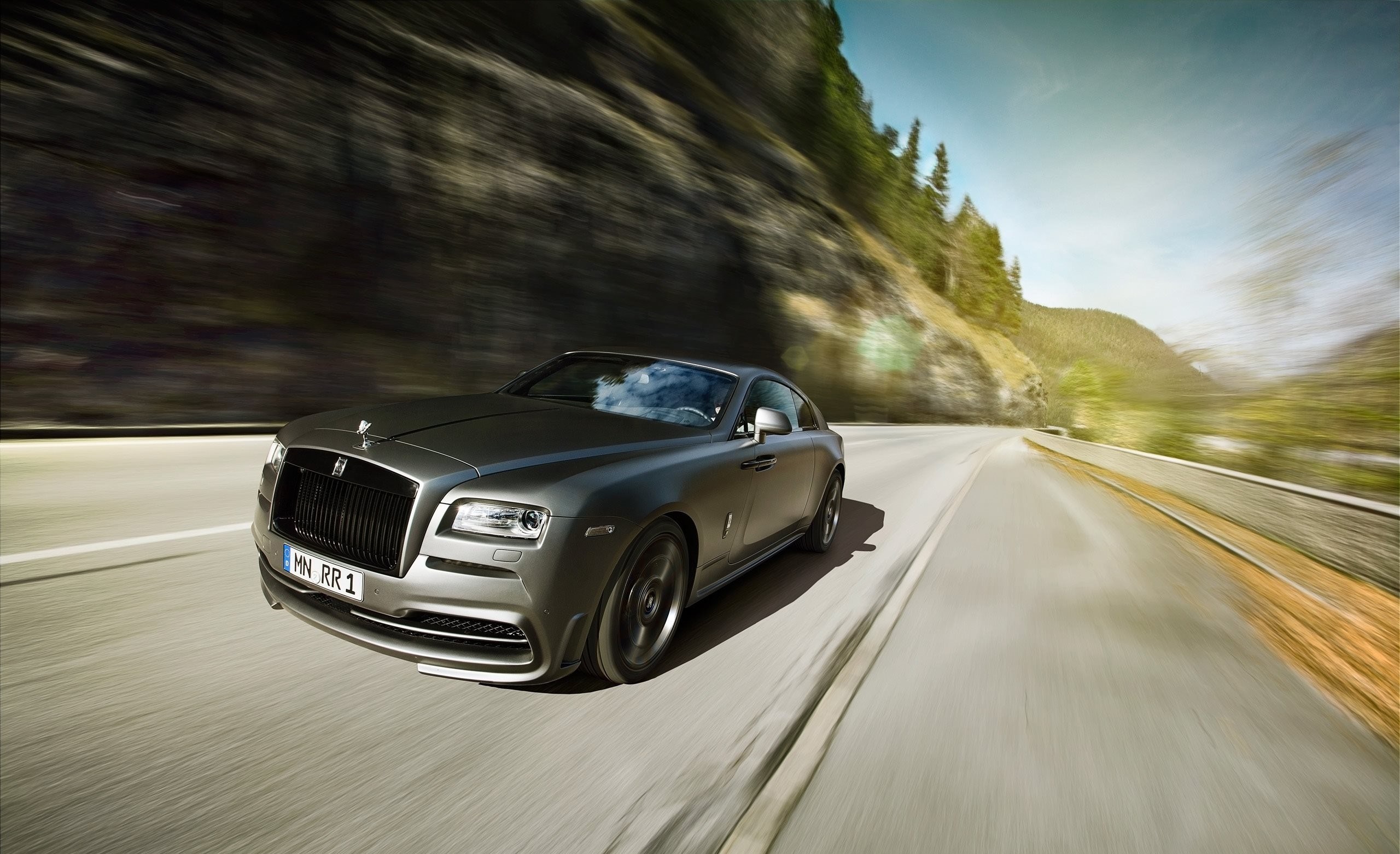 Free photo A gray Rolls Royce Wraith driving down a country road.