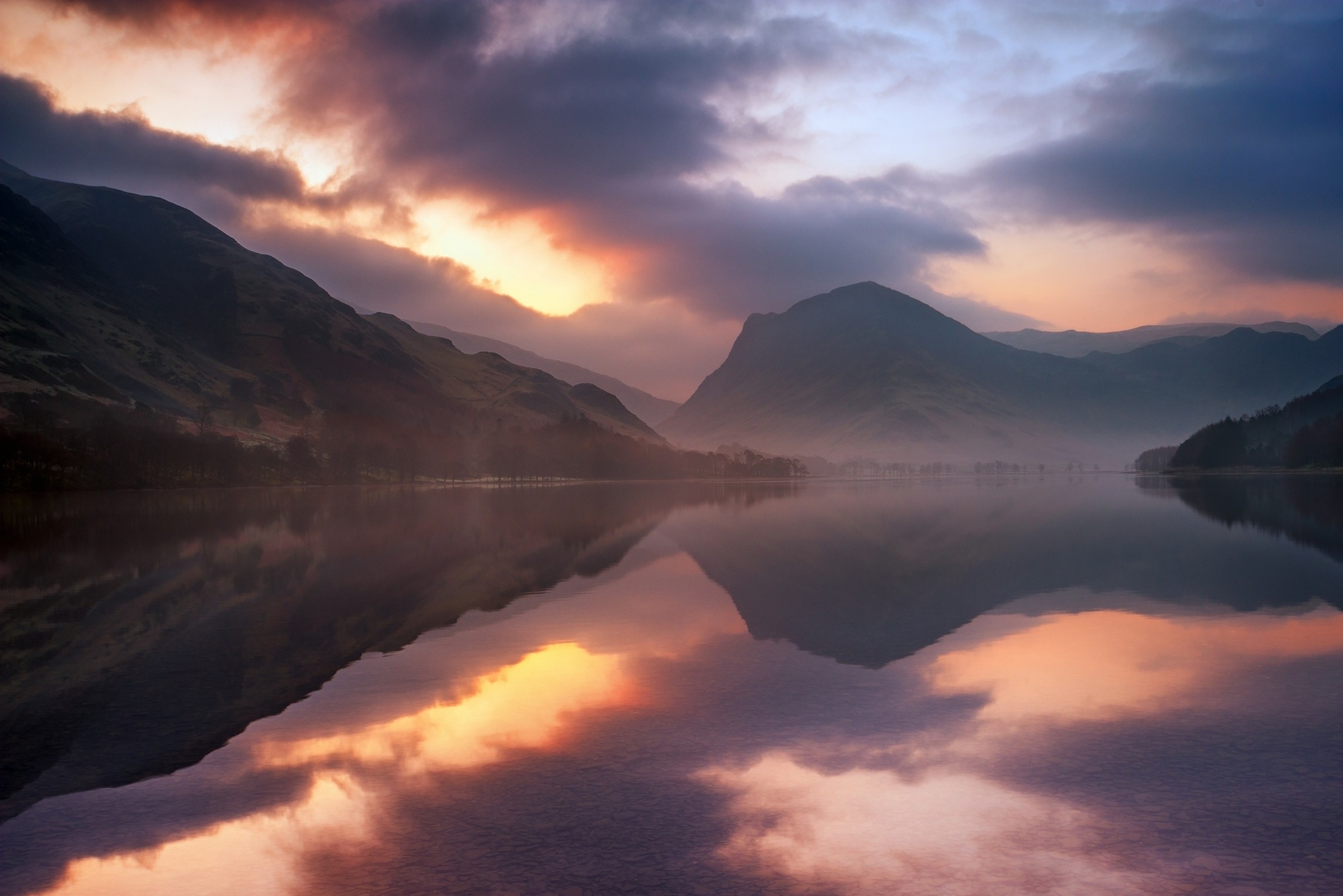 Бесплатное фото Озеро с отражением гор и неба в теплых оттенках заката.