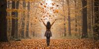 Woman standing in leaves covering floor in fall