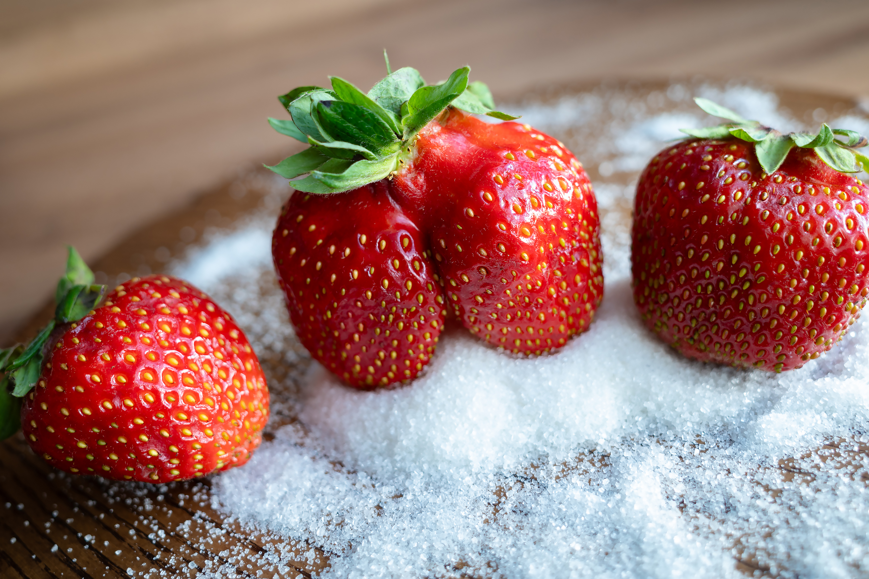 Бесплатное фото Три ягоды клубники в сахарном песке