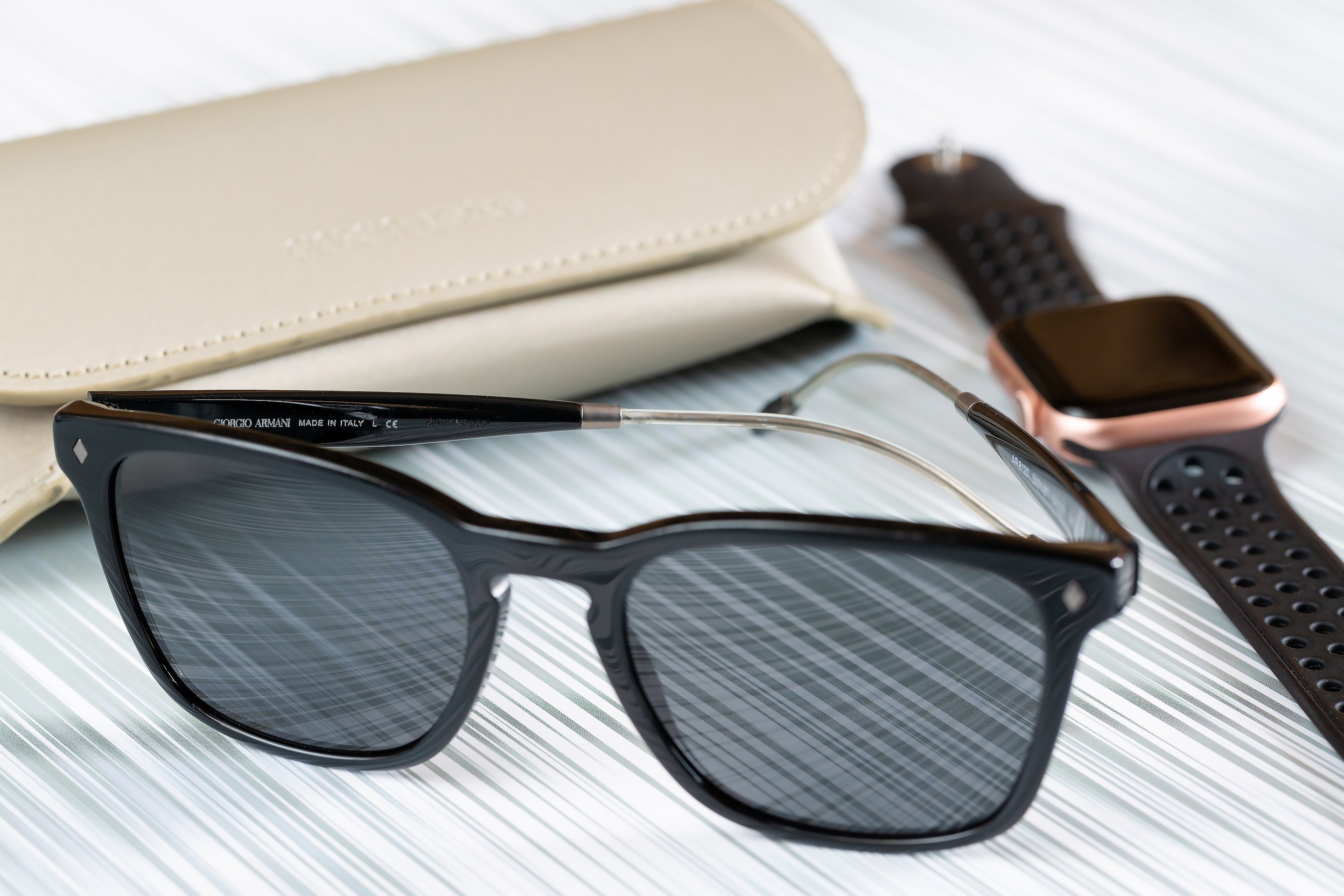 Солнцезащитные очки и умные часы на полосатом фоне