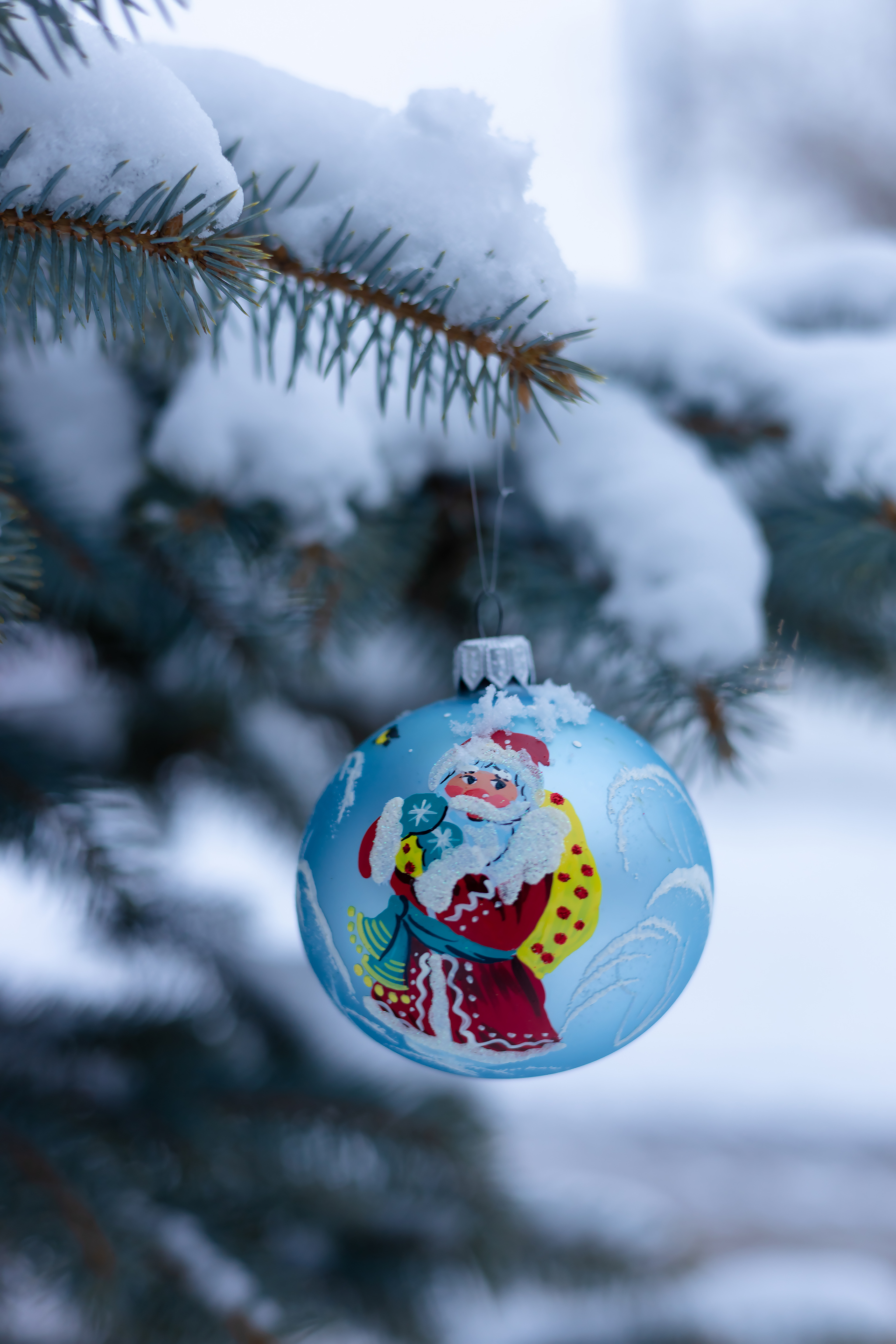 Бесплатное фото Новогодний шар на заснеженной ветке голубой ёлки