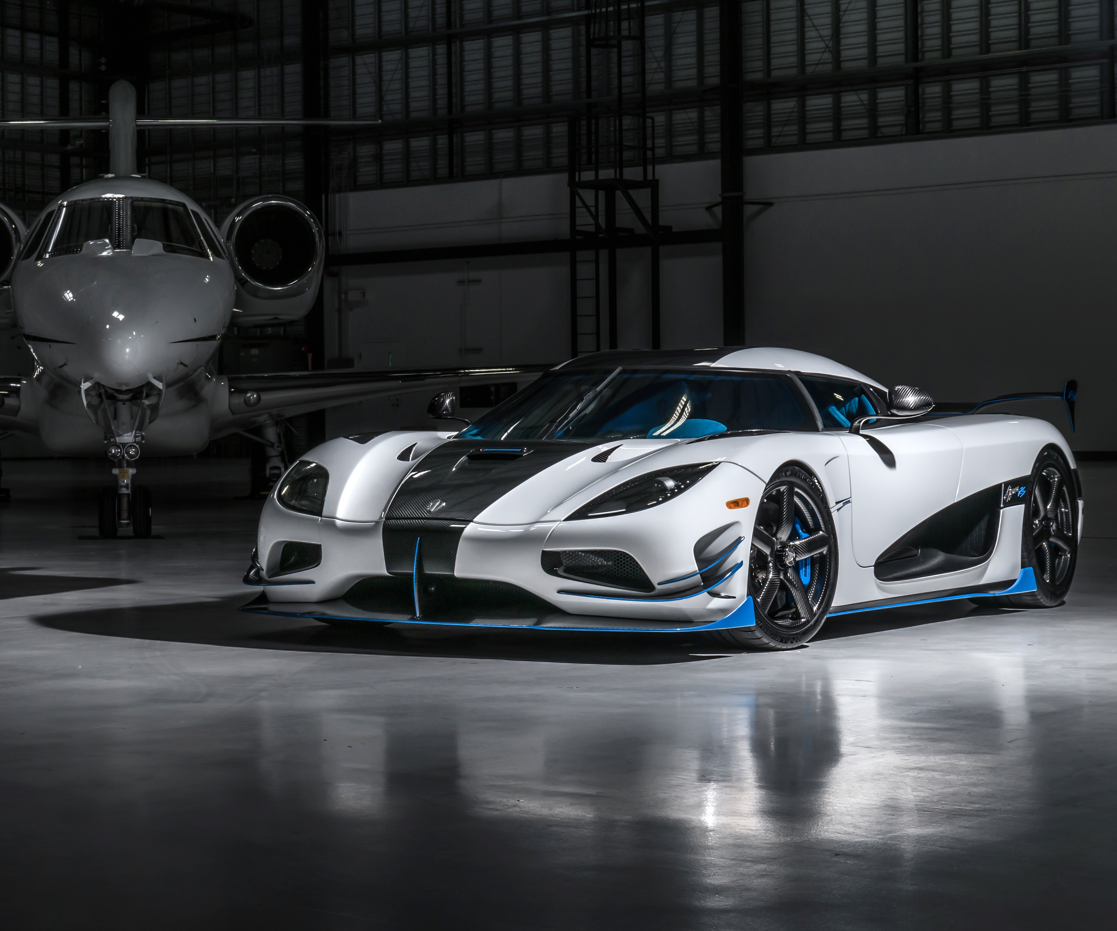 Бесплатное фото Белый koenigsegg agera rs1 рядом с самолетом