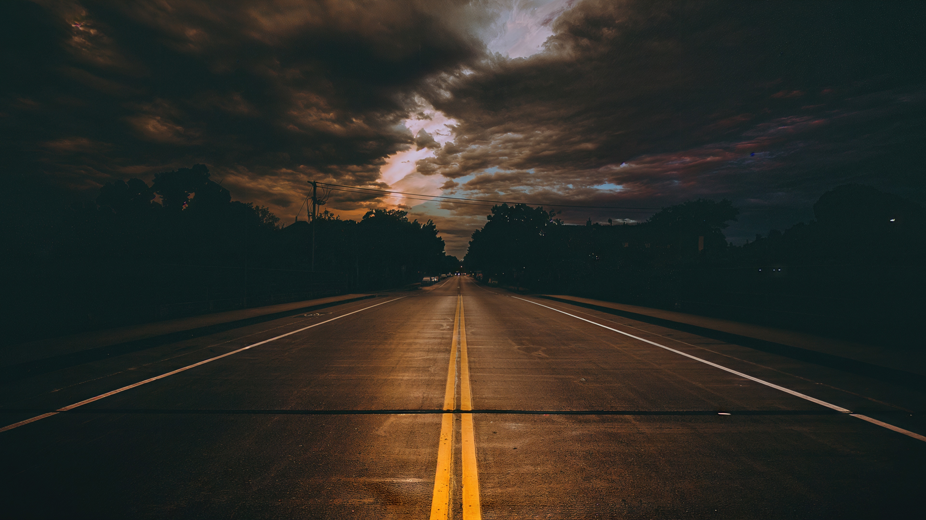 Free photo The road goes off into the distance under a dramatic cloudy sky.