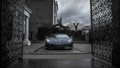 Бесплатное фото Черная матовая Ламборгини заезжает во двор особняка