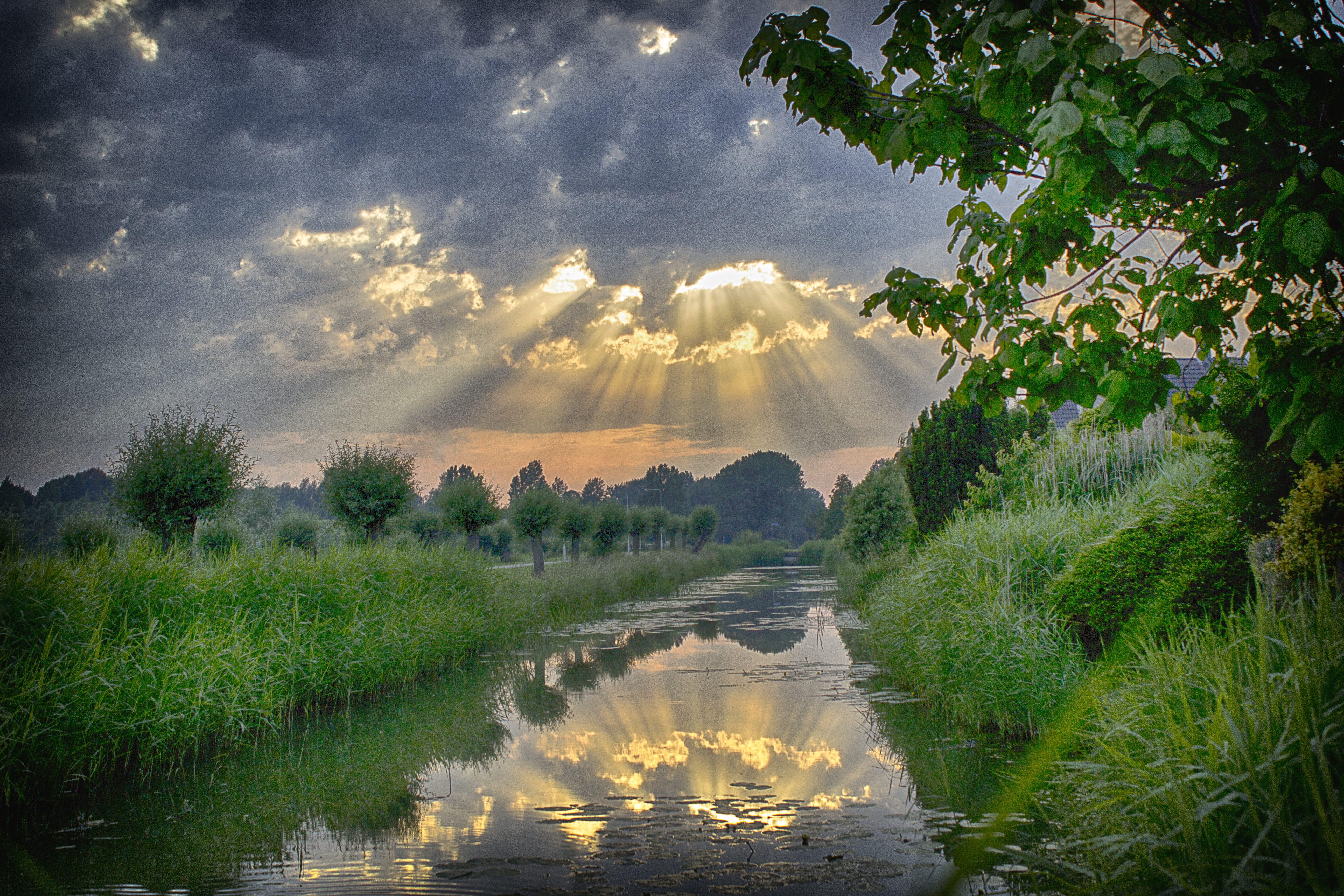 Бесплатное фото Солнечные лучи пробиваются сквозь тучи на речке