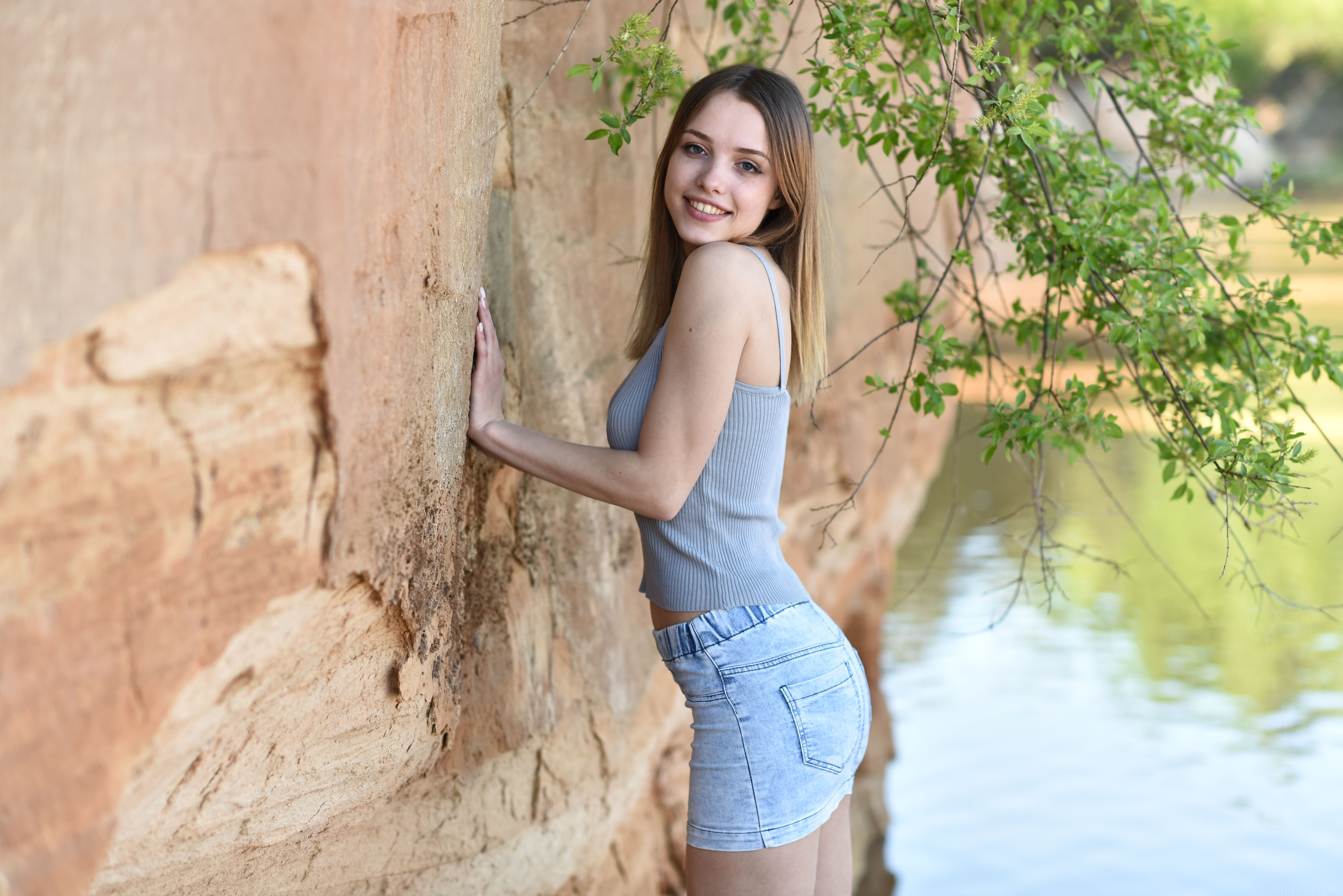 Free photo A girl in short jean shorts is standing against the wall