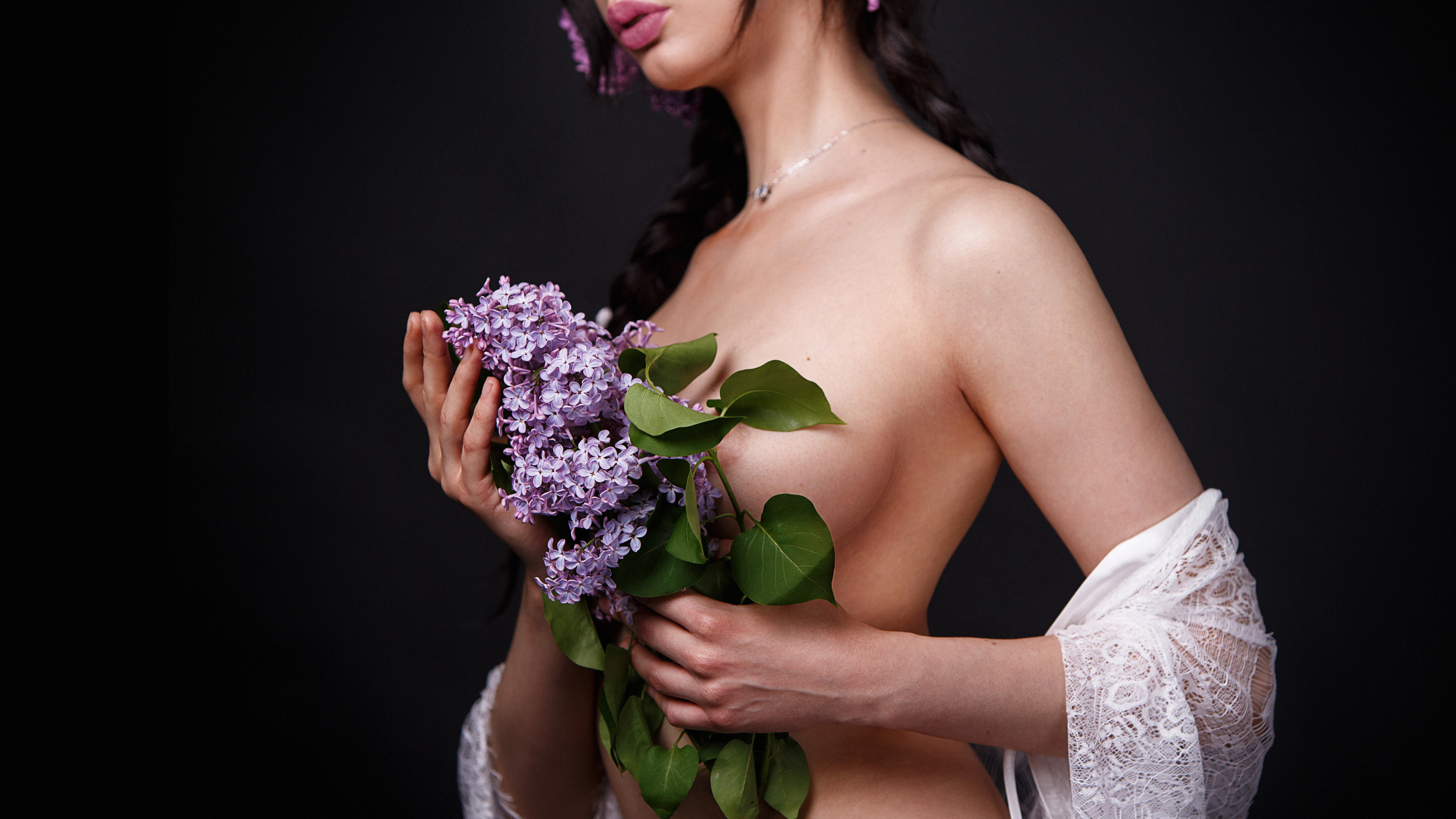 Free photo The girl covered her naked breasts with a bouquet of lilacs.